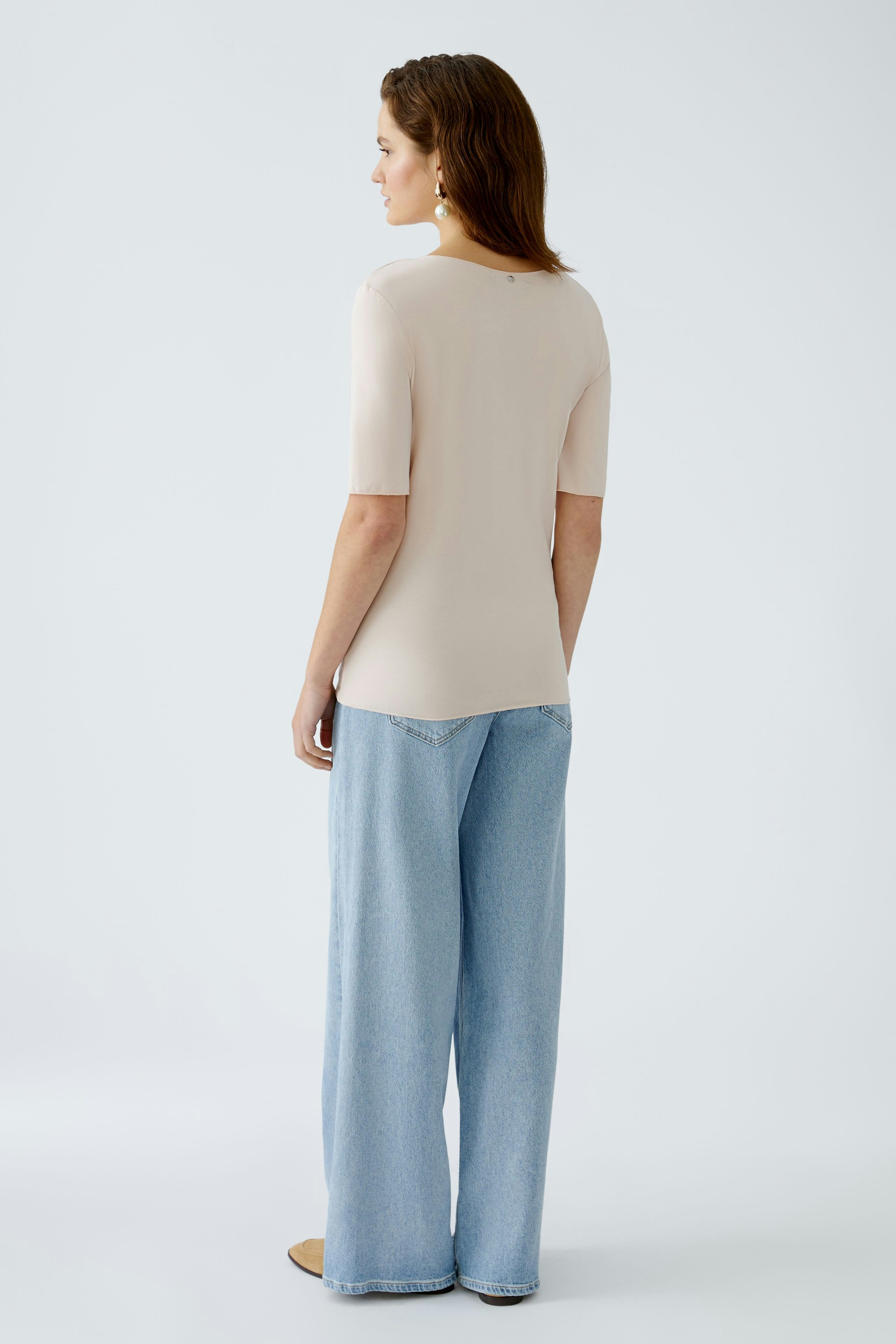 Elegant women's T-shirt: A woman in a fitted beige T-shirt paired with wide-leg jeans.