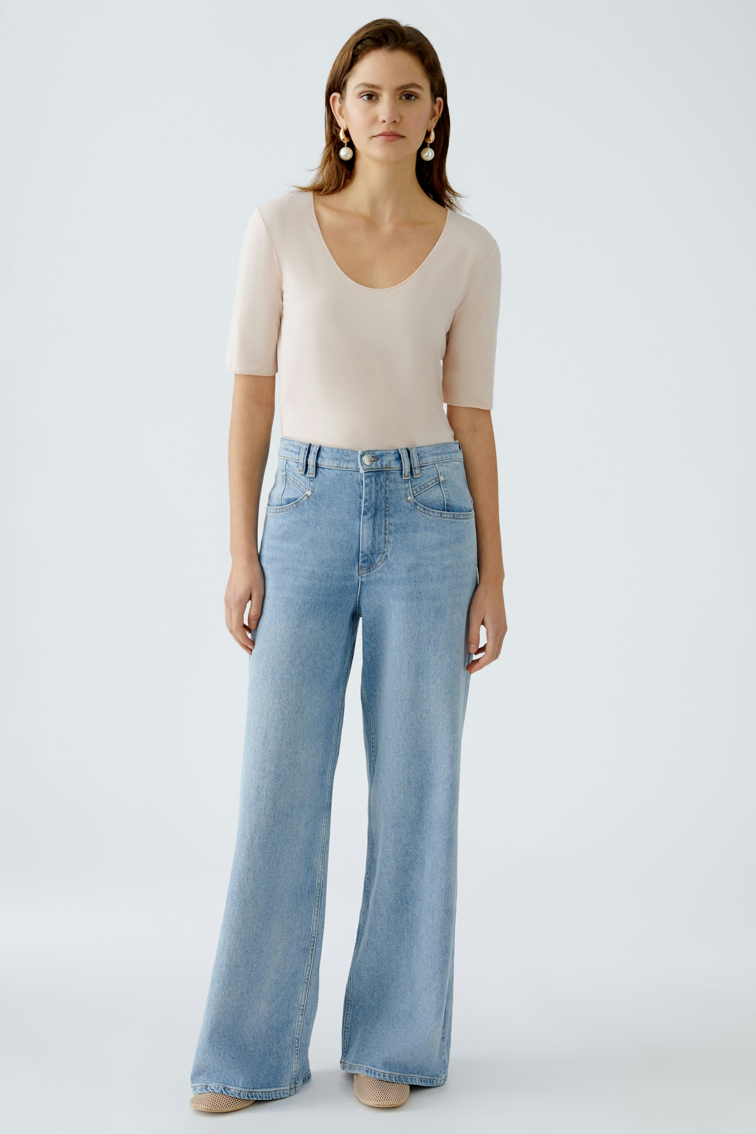 Elegant women's T-shirt in soft fabric, paired with light blue wide-leg jeans.