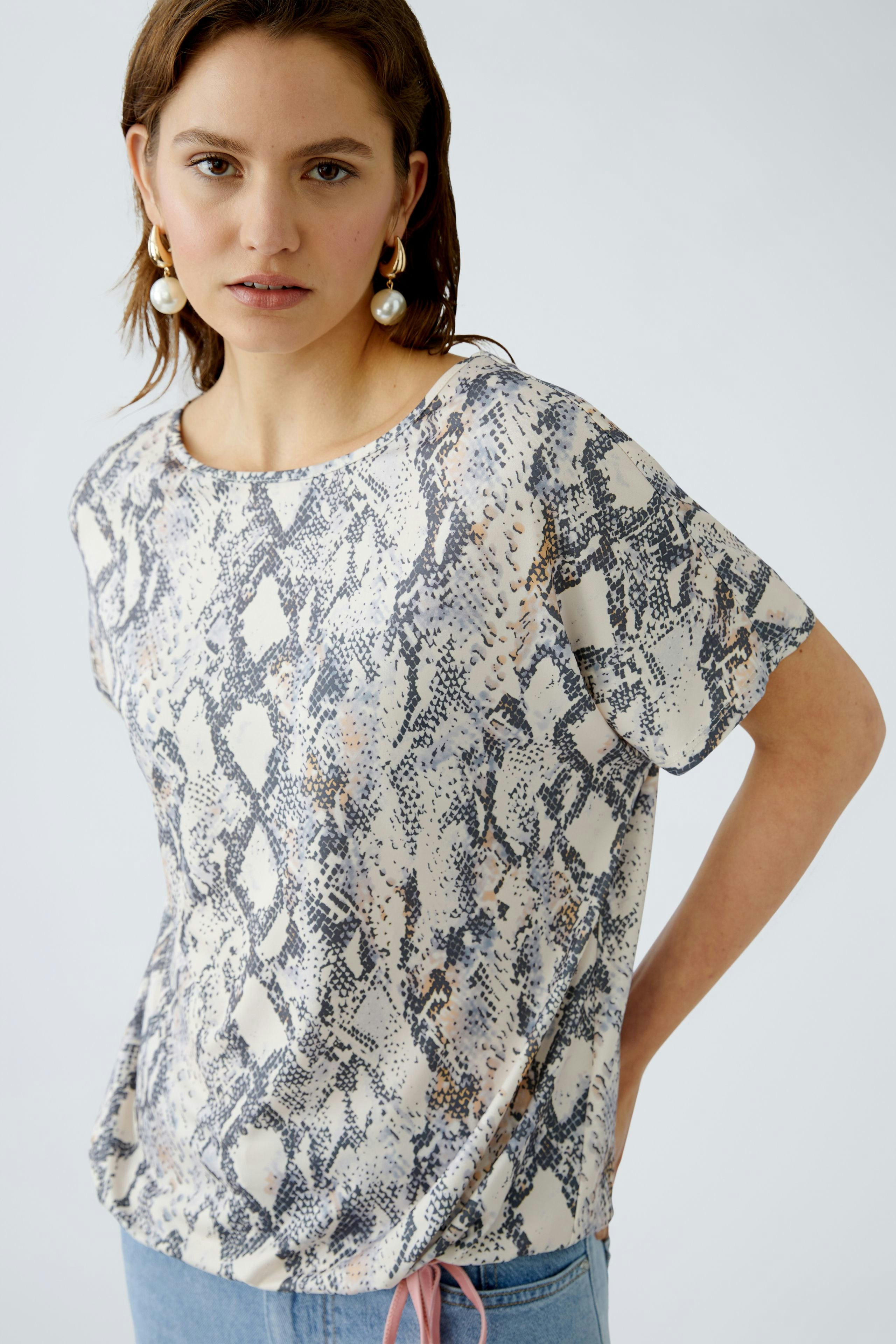 Damen-T-Shirt mit Schlangenmuster: Frau trägt ein leichtes, lässiges Oberteil in sanften Farben.