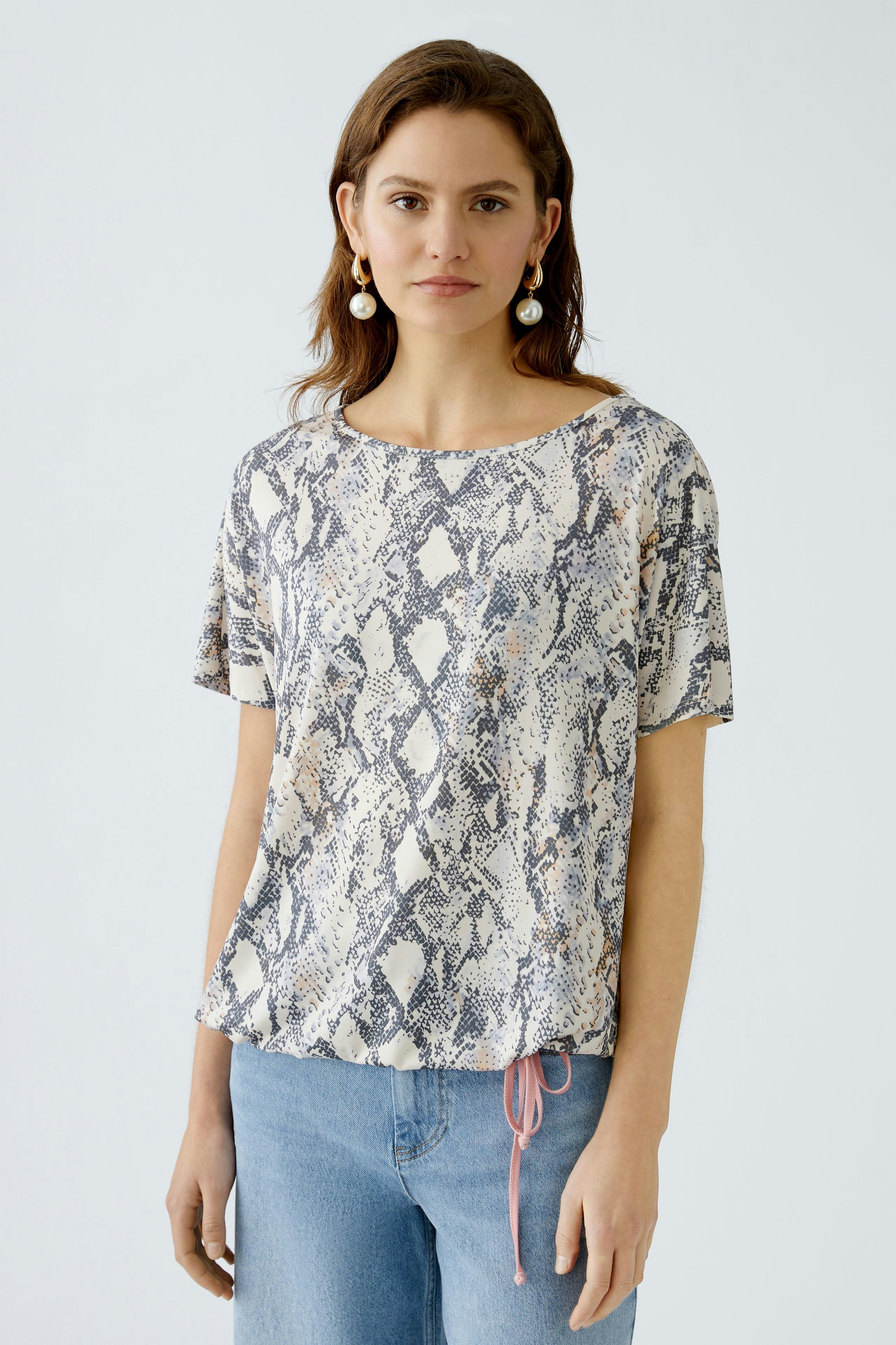 Damen-T-Shirt im Schlangenprint: Frau trägt ein lässiges, gemustertes Oberteil mit Rundhalsausschnitt.