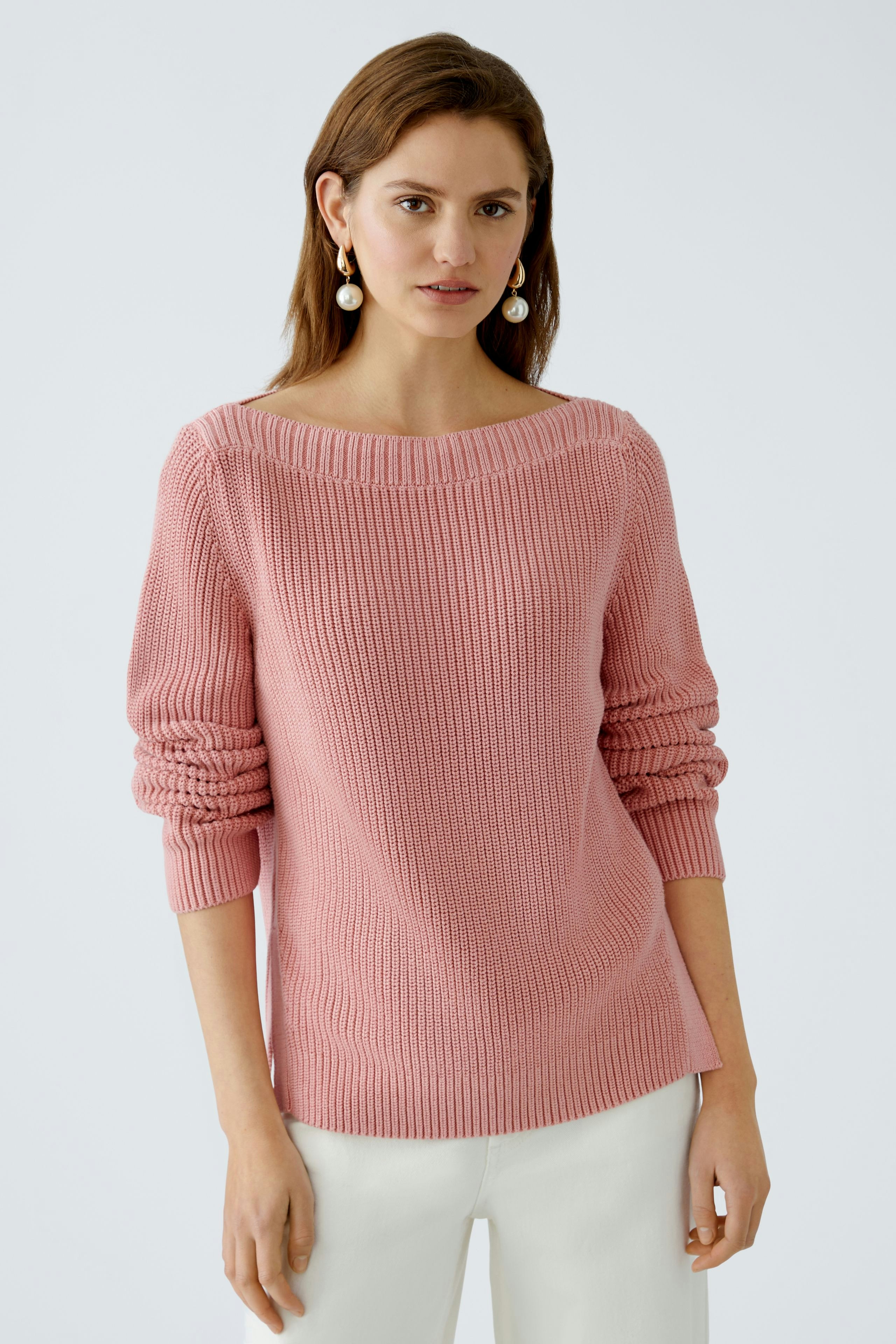 Modern women's pullover: A woman in a soft pink knitted pullover with a relaxed fit.
