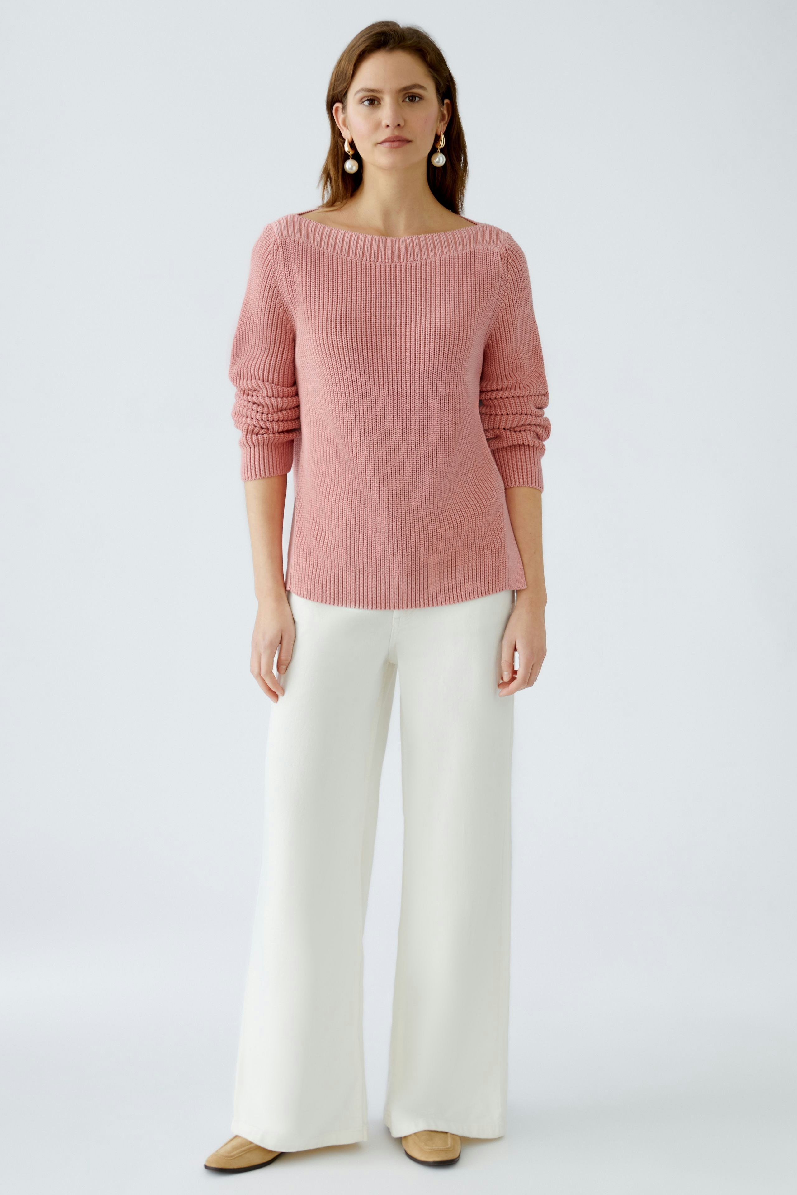 Stylish women's pullover: A woman in a pink knitted pullover with a relaxed fit and elegant wide-leg pants.