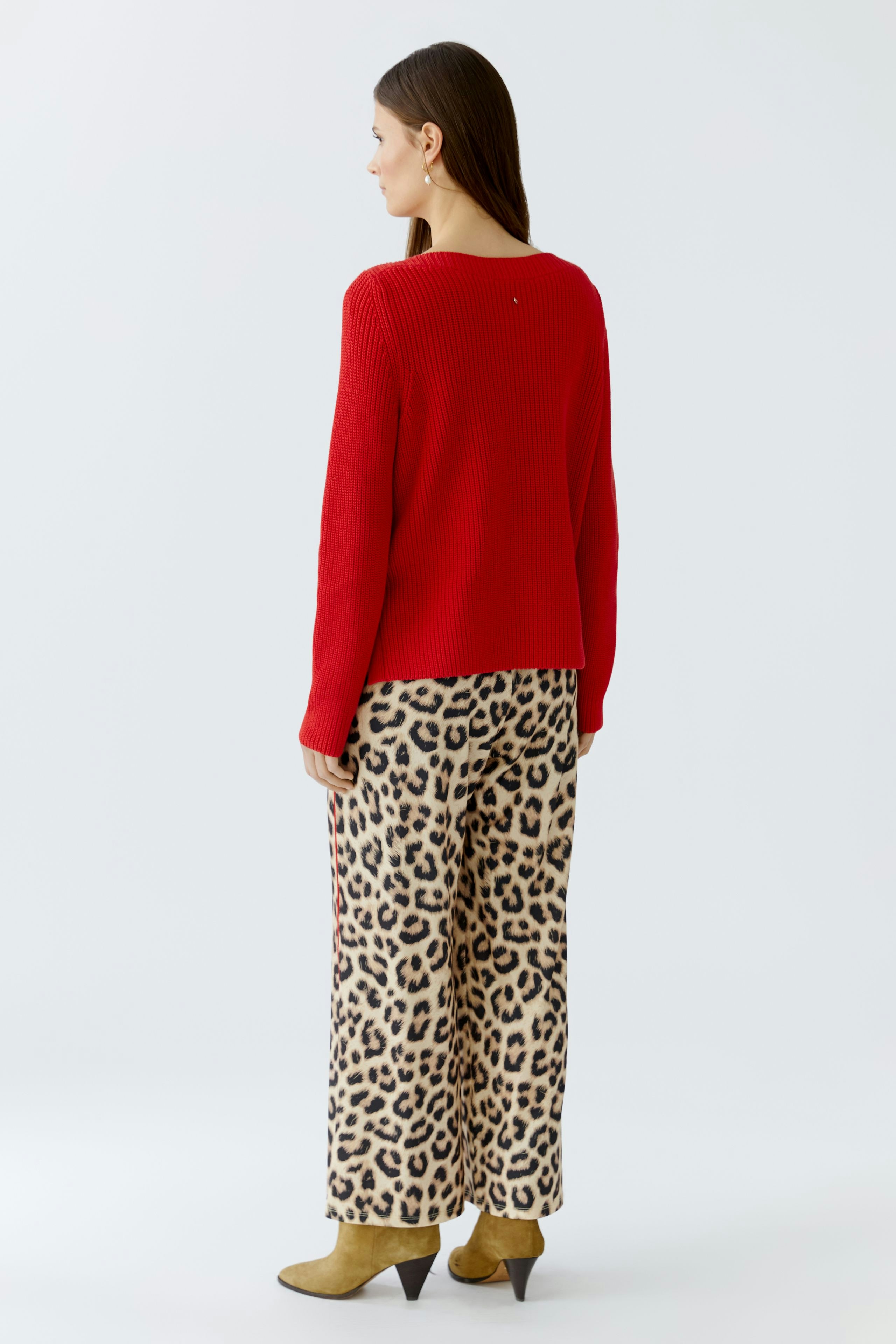 Stylish women's pullover: A woman in a vibrant red knit pullover paired with leopard print pants.