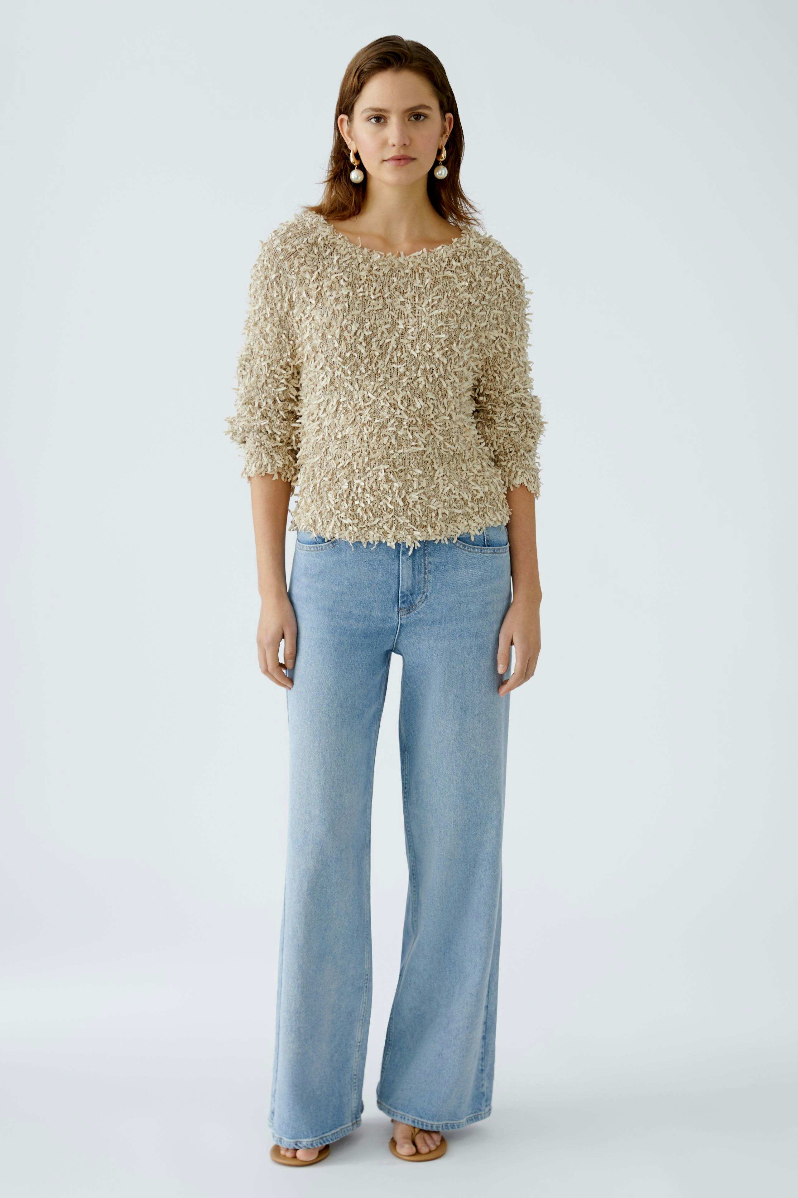 Beiger Damen-Pullover: Frau trägt einen flauschigen Pullover mit weitem Schnitt und lässigen Jeans.