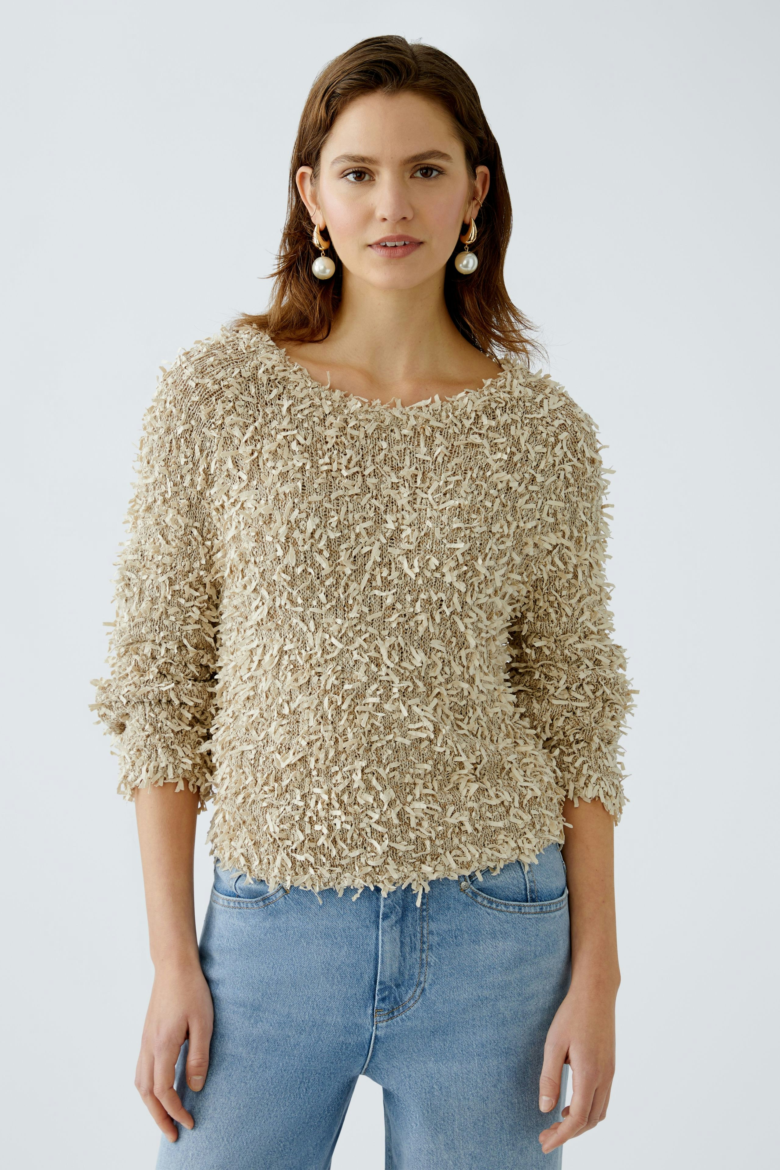 Beiger Damen-Pullover: Frau trägt einen flauschigen Pullover mit weitem Ausschnitt und lässigen Jeans.