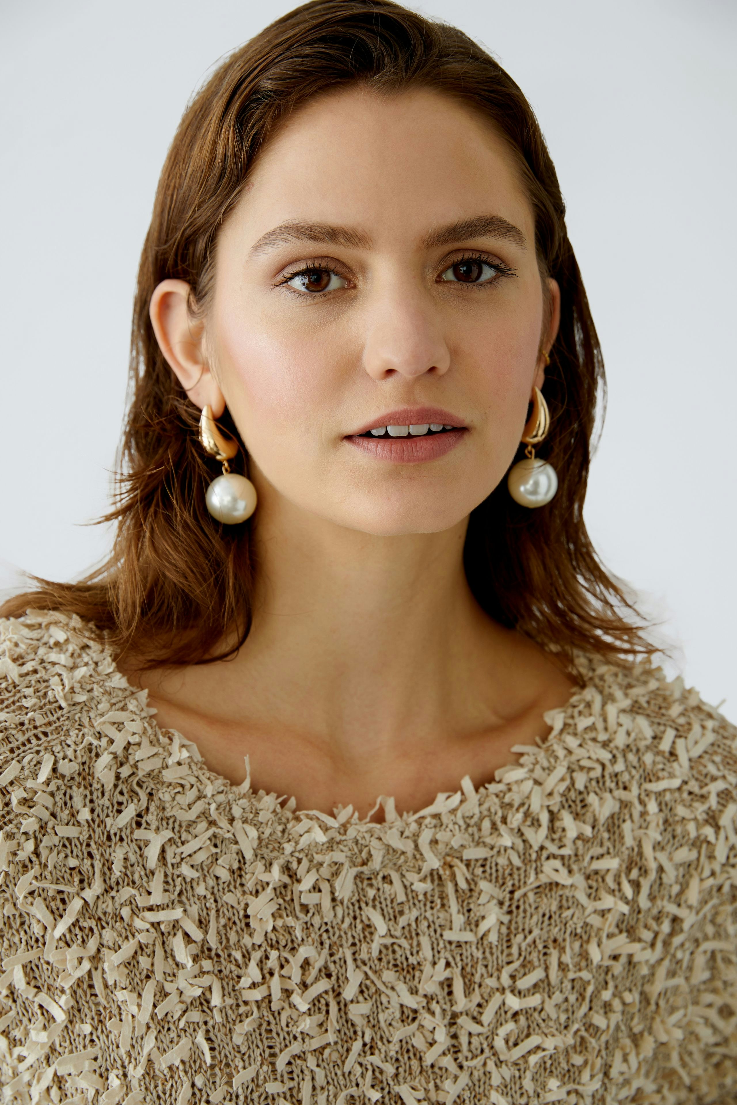 Damen-Pullover: Frau trägt einen beigen, strukturierten Pullover mit fransigen Details.