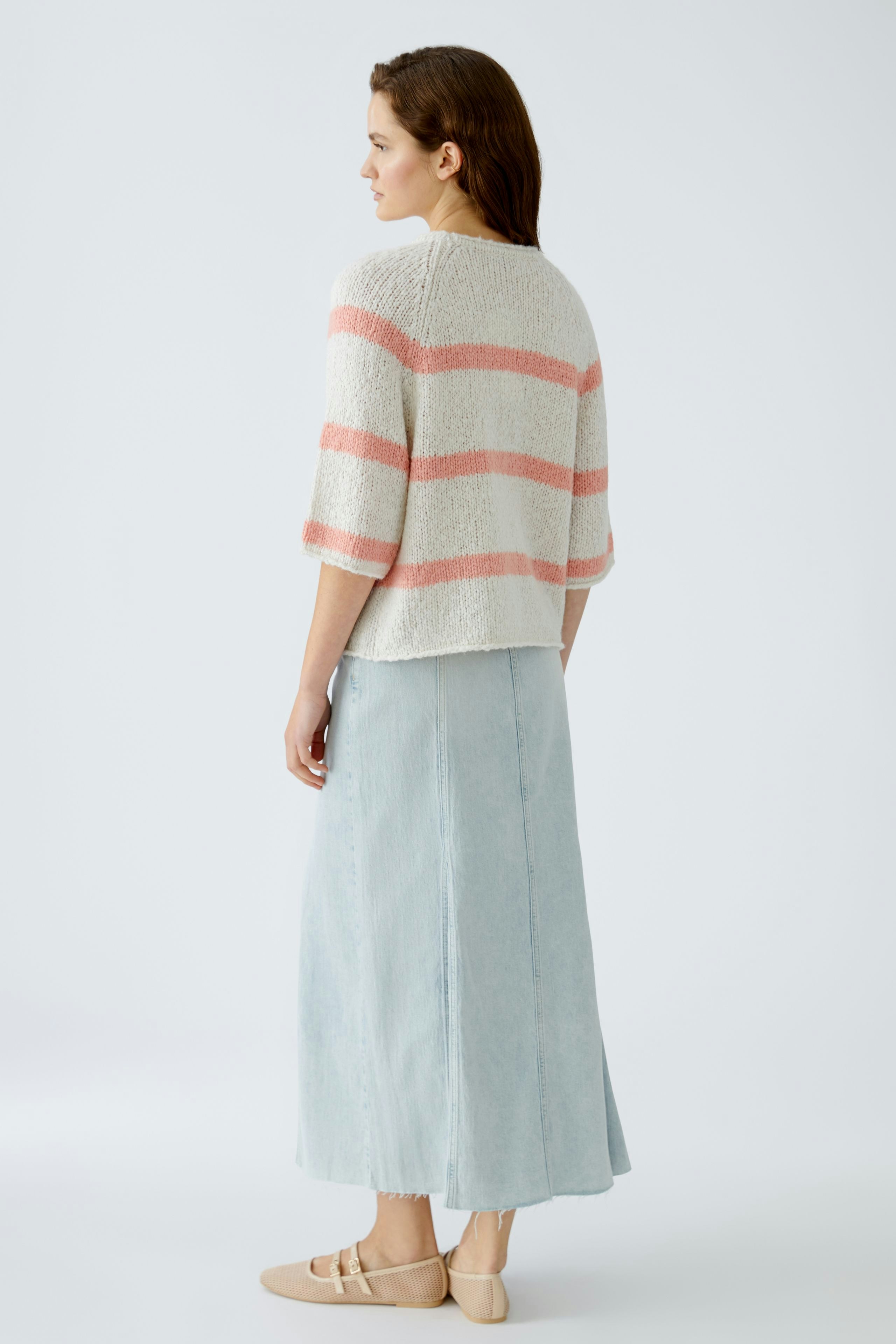 Damen-Pullover: Frau trägt einen gestreiften, lässigen Pullover in sanften Farben.