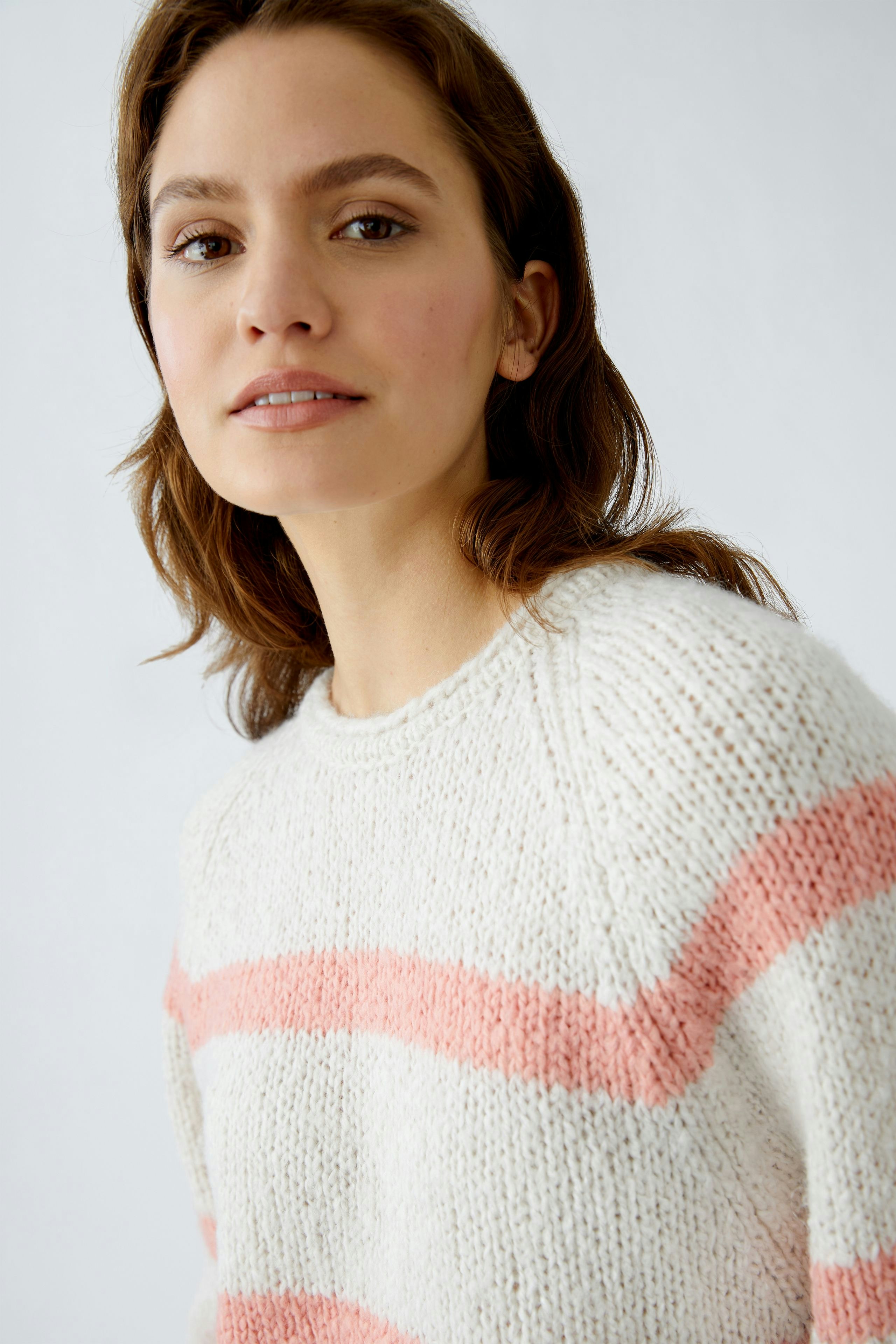 Damen-Pullover: Frau trägt einen lässigen, gestreiften Pullover in Creme und Rosa.