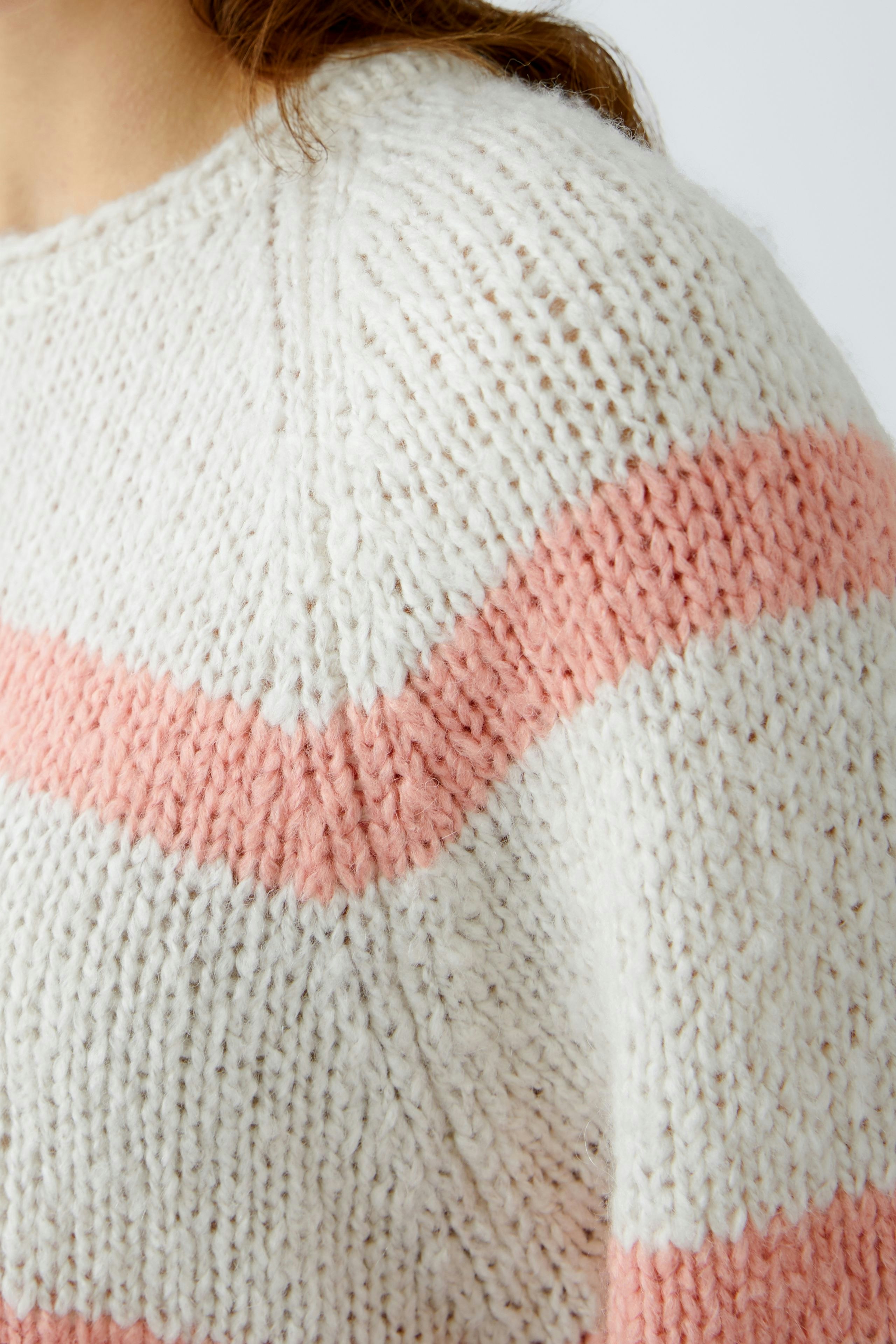 Damen-Pullover: Frau trägt einen gemütlichen, gestreiften Pullover in sanften Farben.