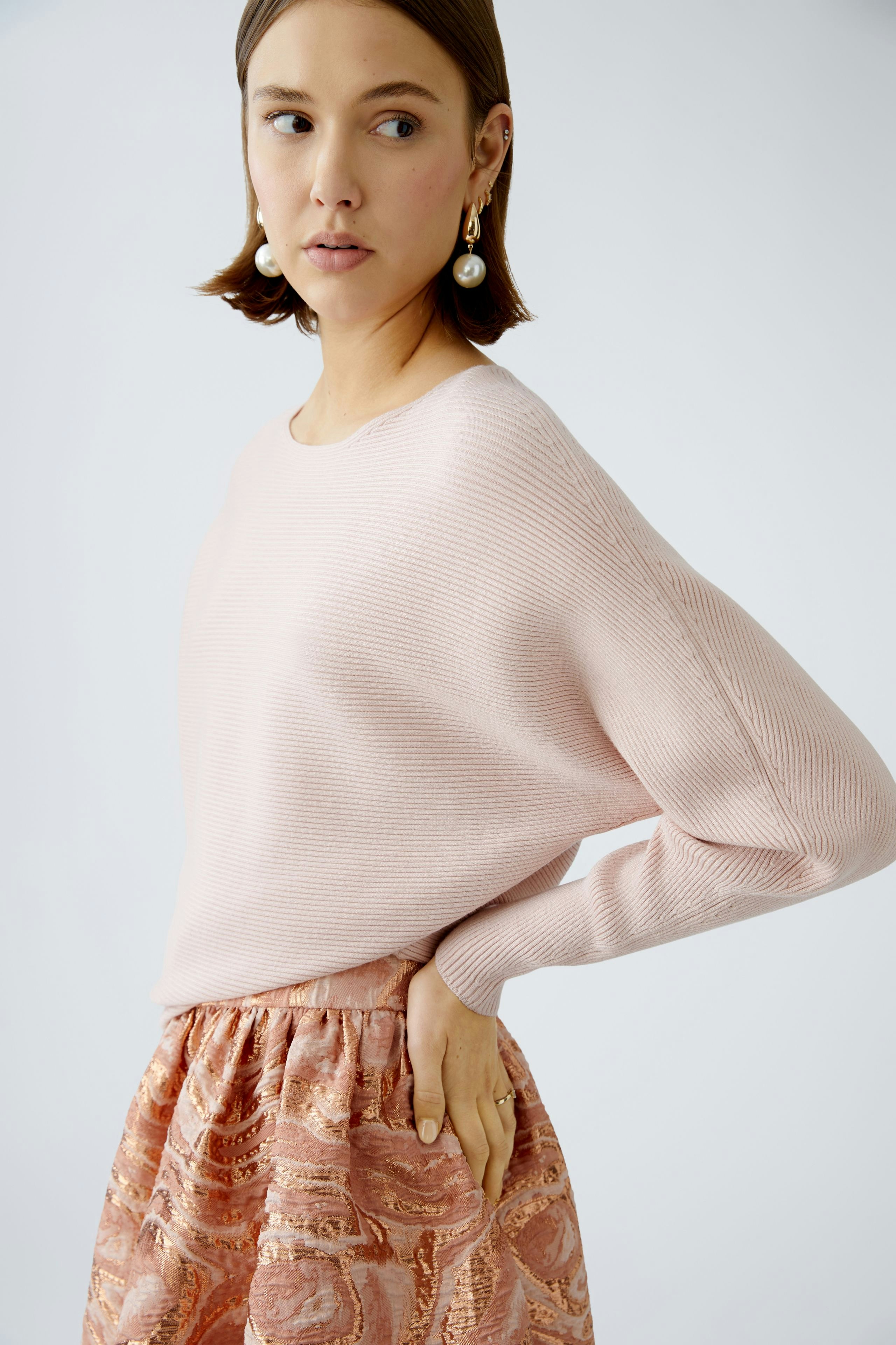 Eleganter Damen-Pullover in zartem Rosa, kombiniert mit einem fließenden Rock für einen stilvollen Look.