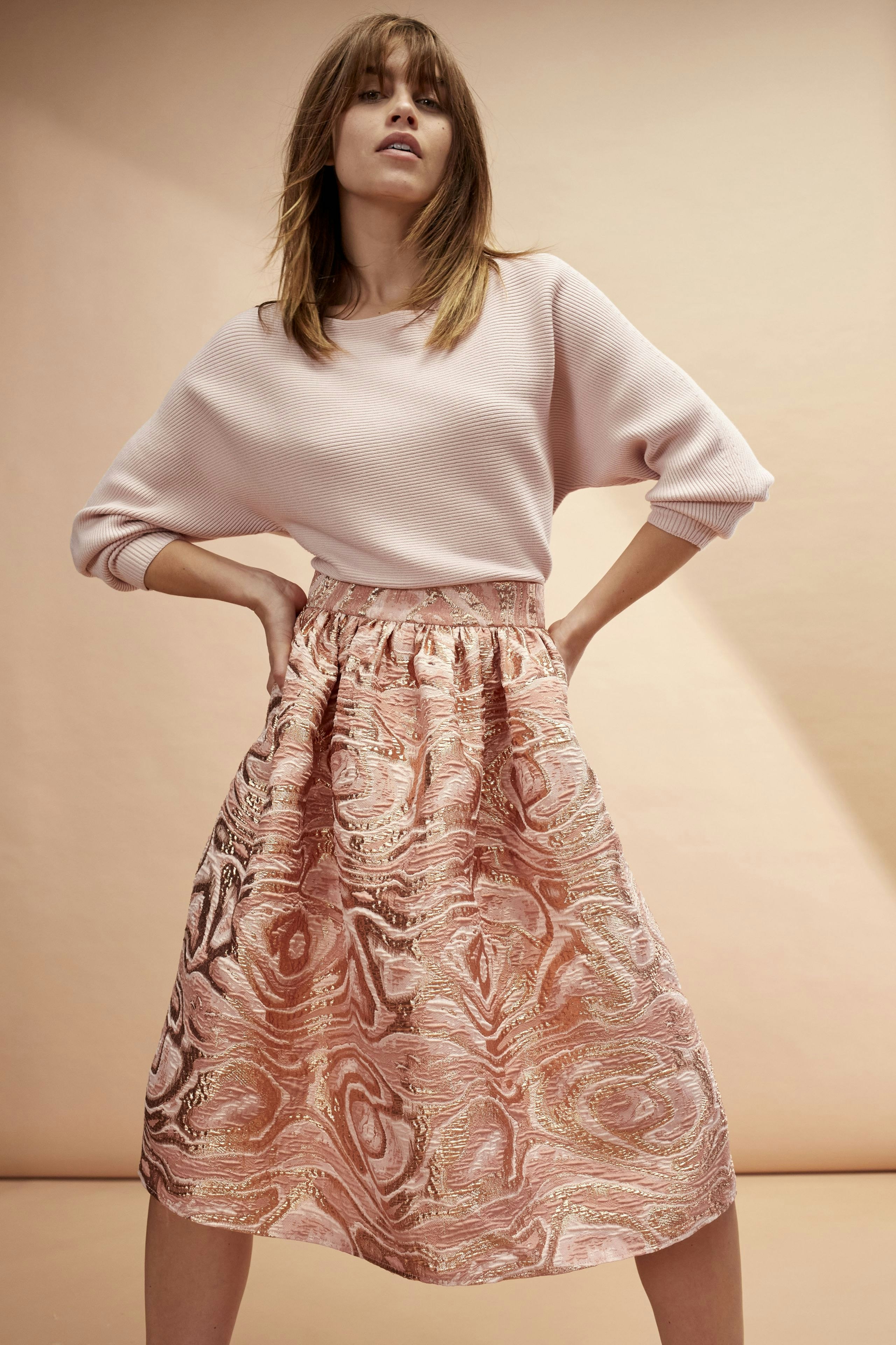 Damen-Pullover: Junge Frau in einem rosa Pullover mit lässigem Schnitt und elegantem Rock.