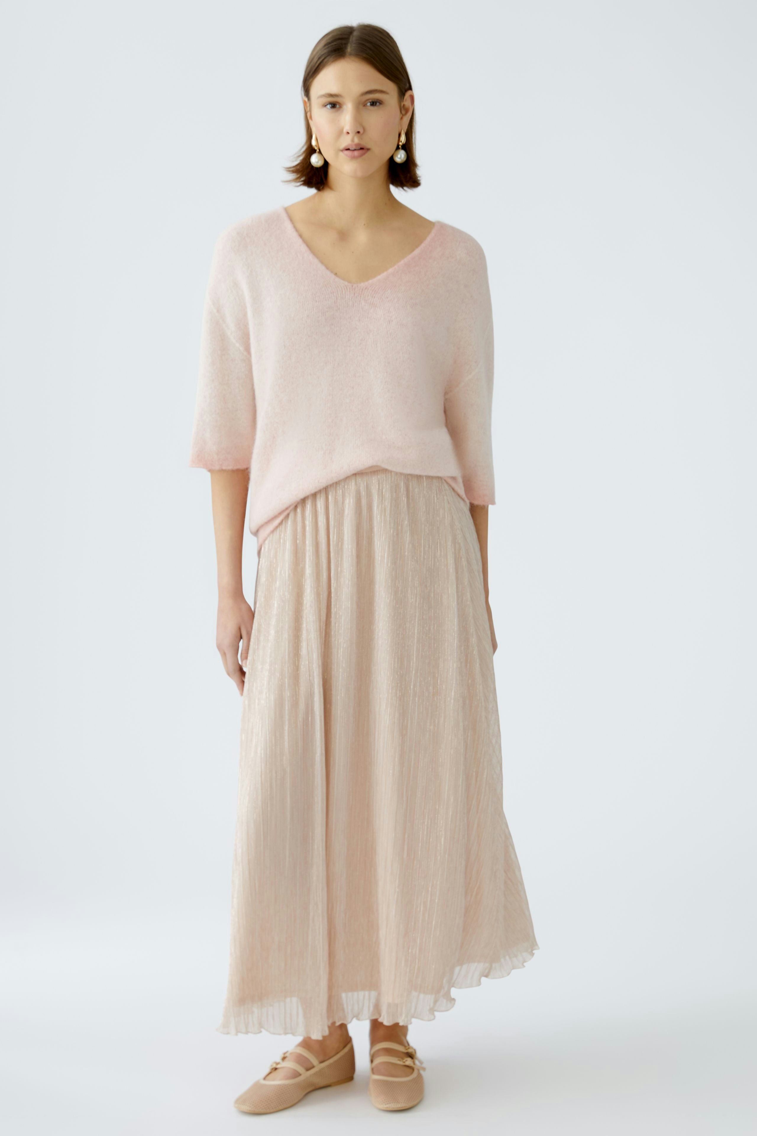 Stylish women's pullover: A woman in a soft pink pullover paired with a flowing skirt.