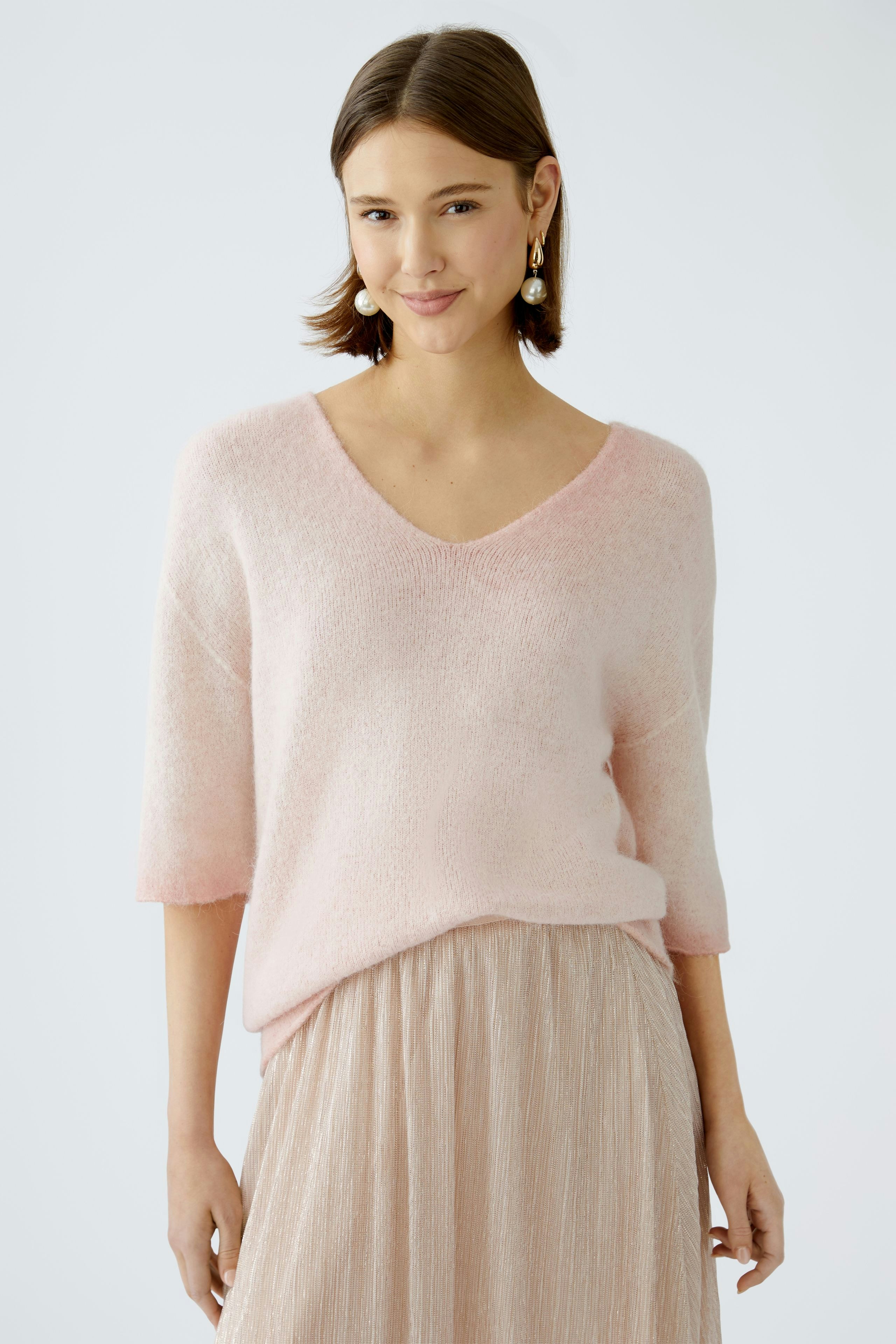Modern women's pullover: A woman in a soft pink pullover with a V-neck and short sleeves.
