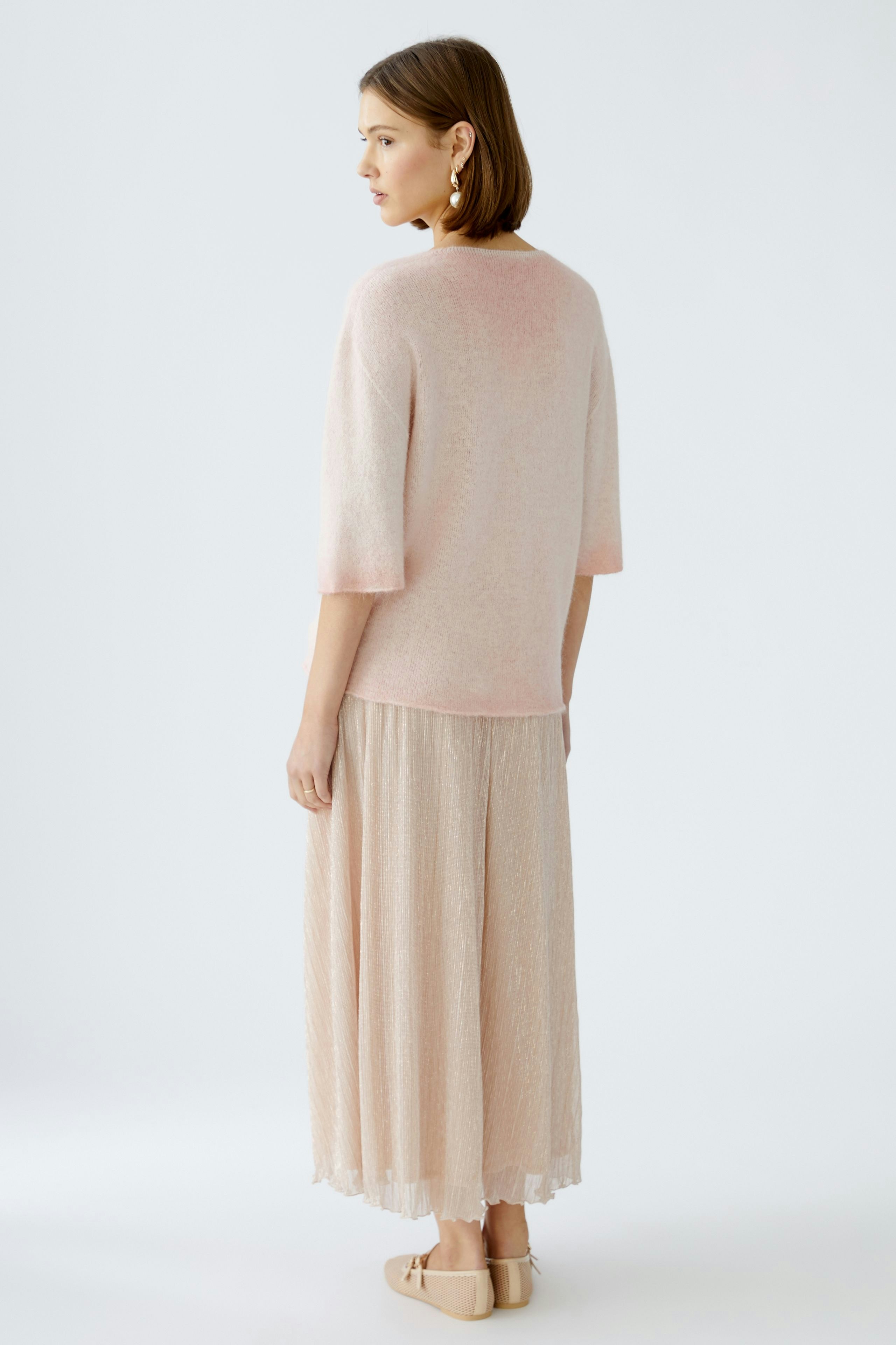 Stylish women's pullover: A woman in a soft pink pullover paired with a flowing skirt.