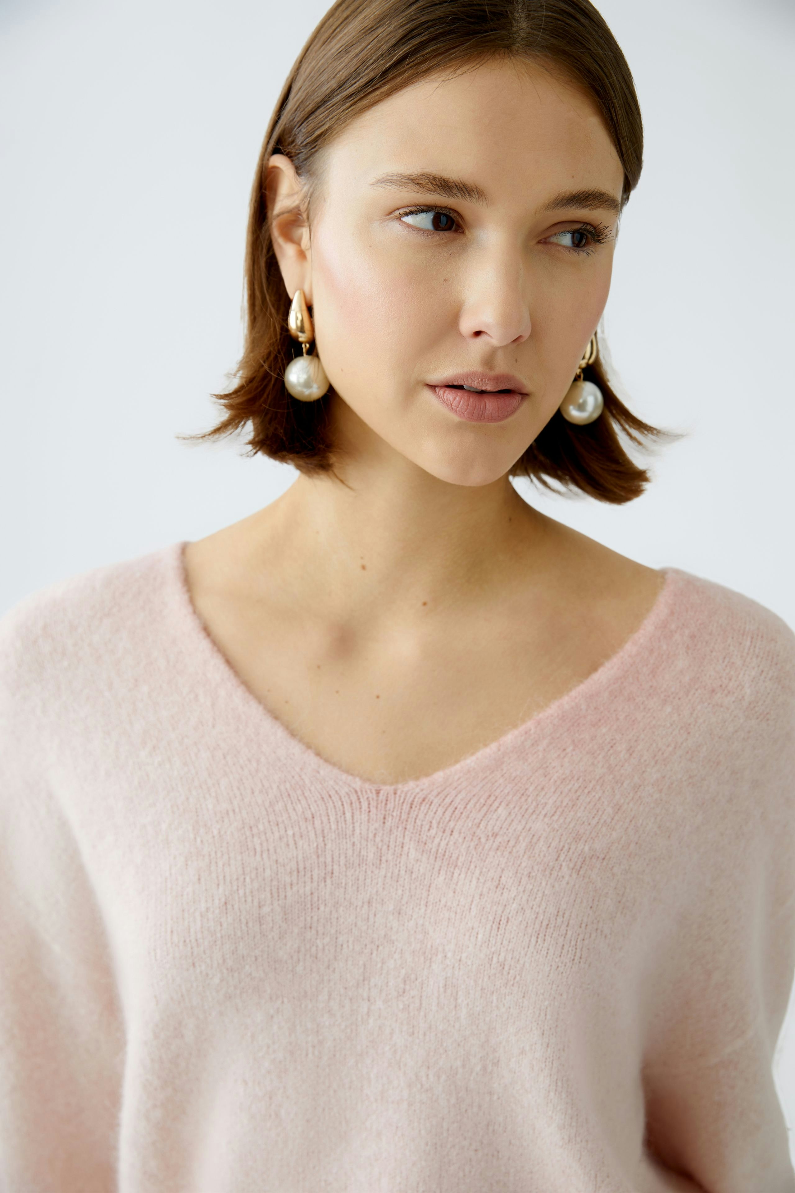 Soft pink pullover: Woman in a cozy V-neck pullover, exuding elegance and comfort.