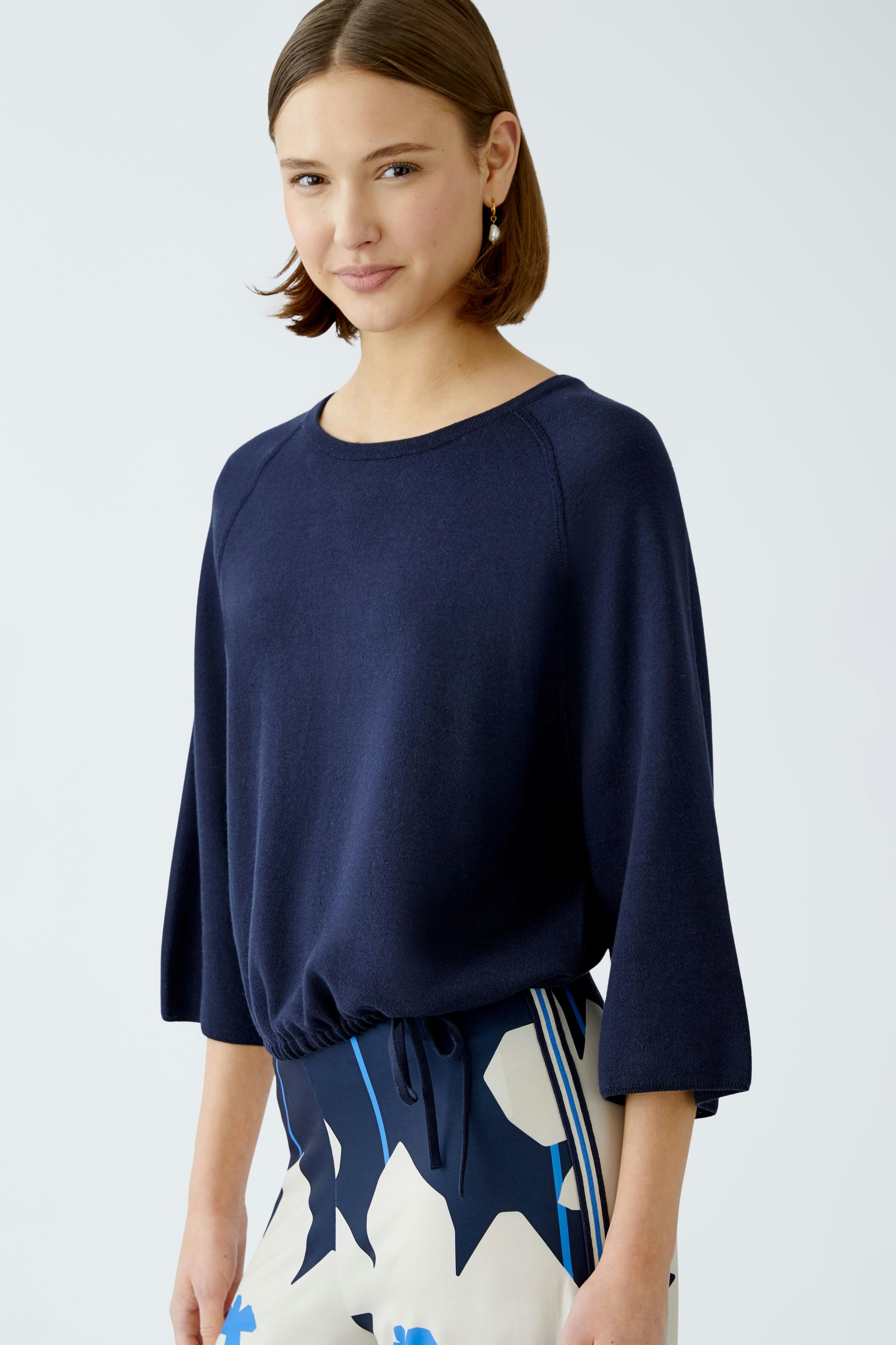 Stylish women's pullover: A woman in a navy pullover with a relaxed fit, paired with a patterned skirt.