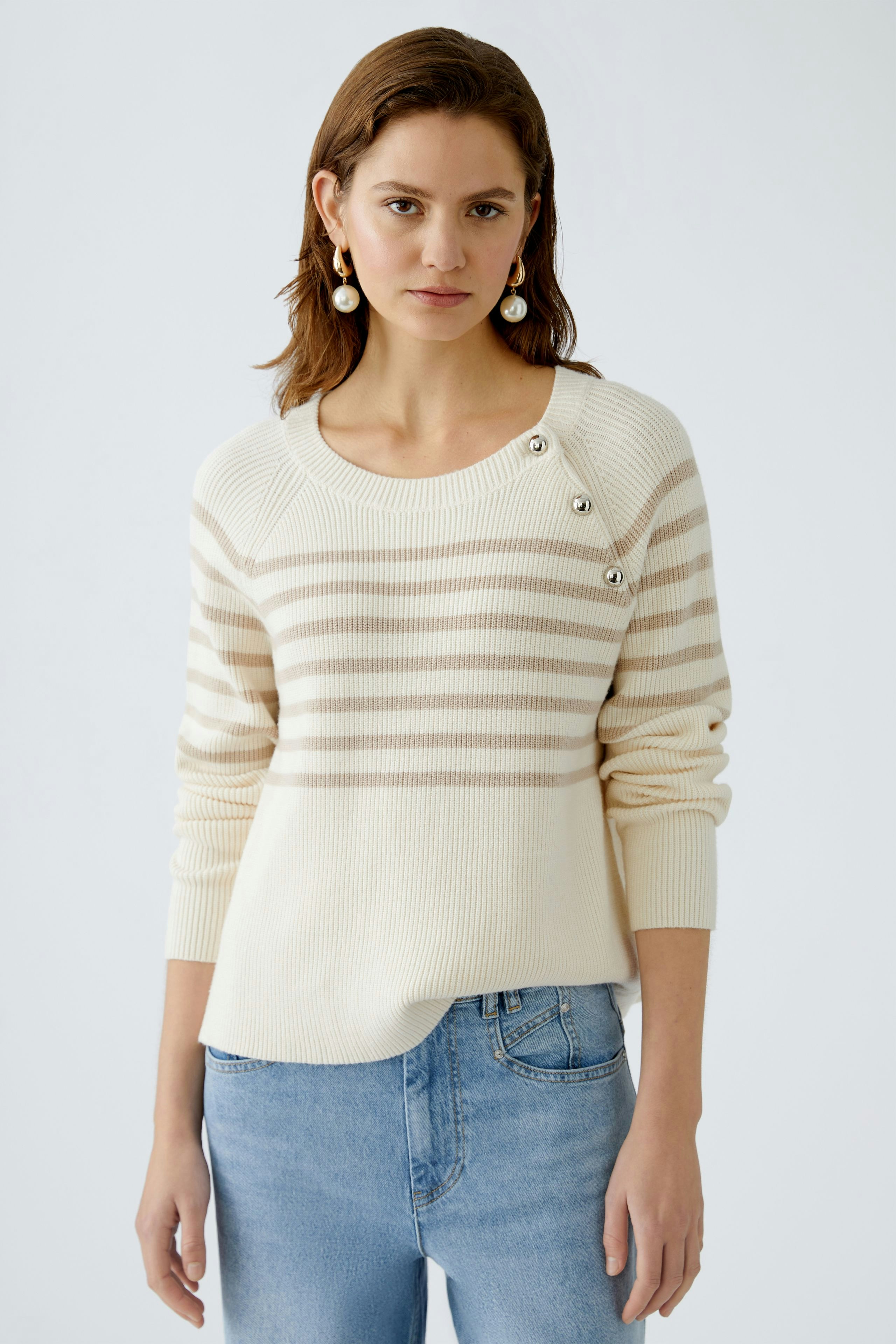 Damen-Pullover: Frau in cremefarbenem, gestreiften Pullover mit Knöpfen und lässigen Jeans.