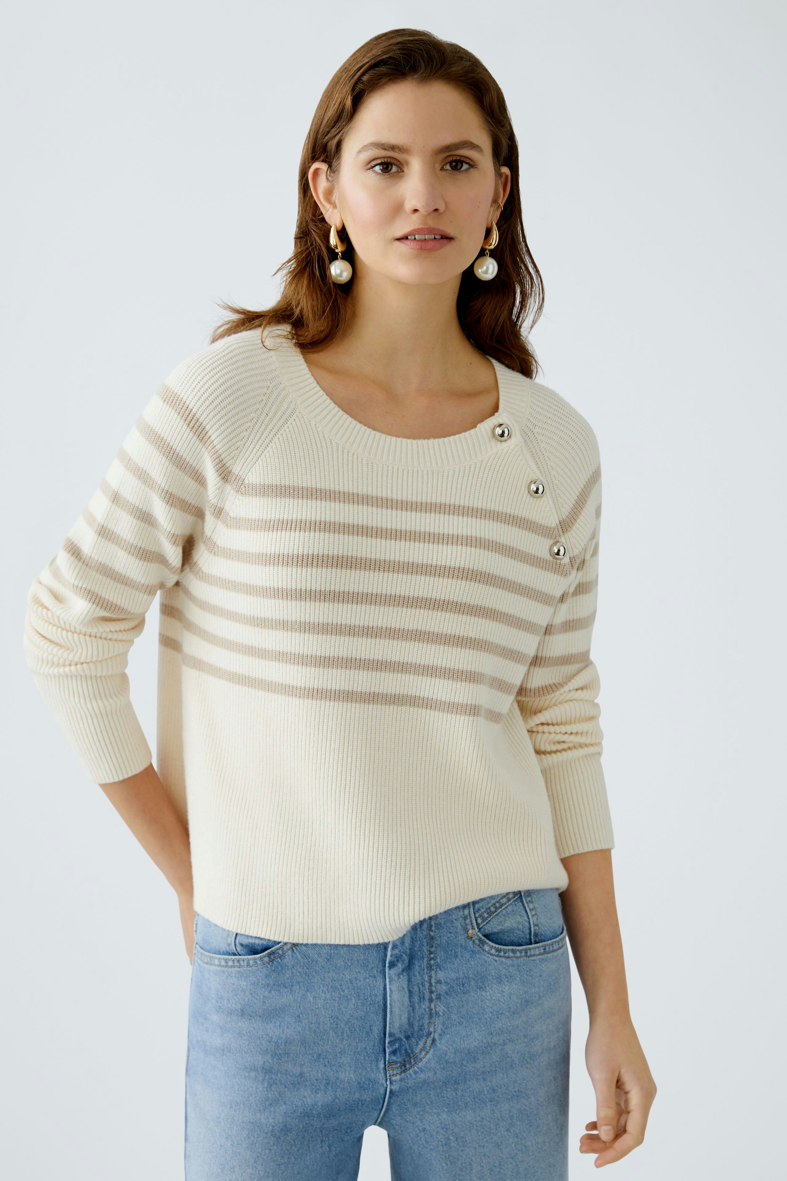 Eleganter Damen-Pullover in Creme mit Streifen und Knöpfen, lässig kombiniert mit Jeans.