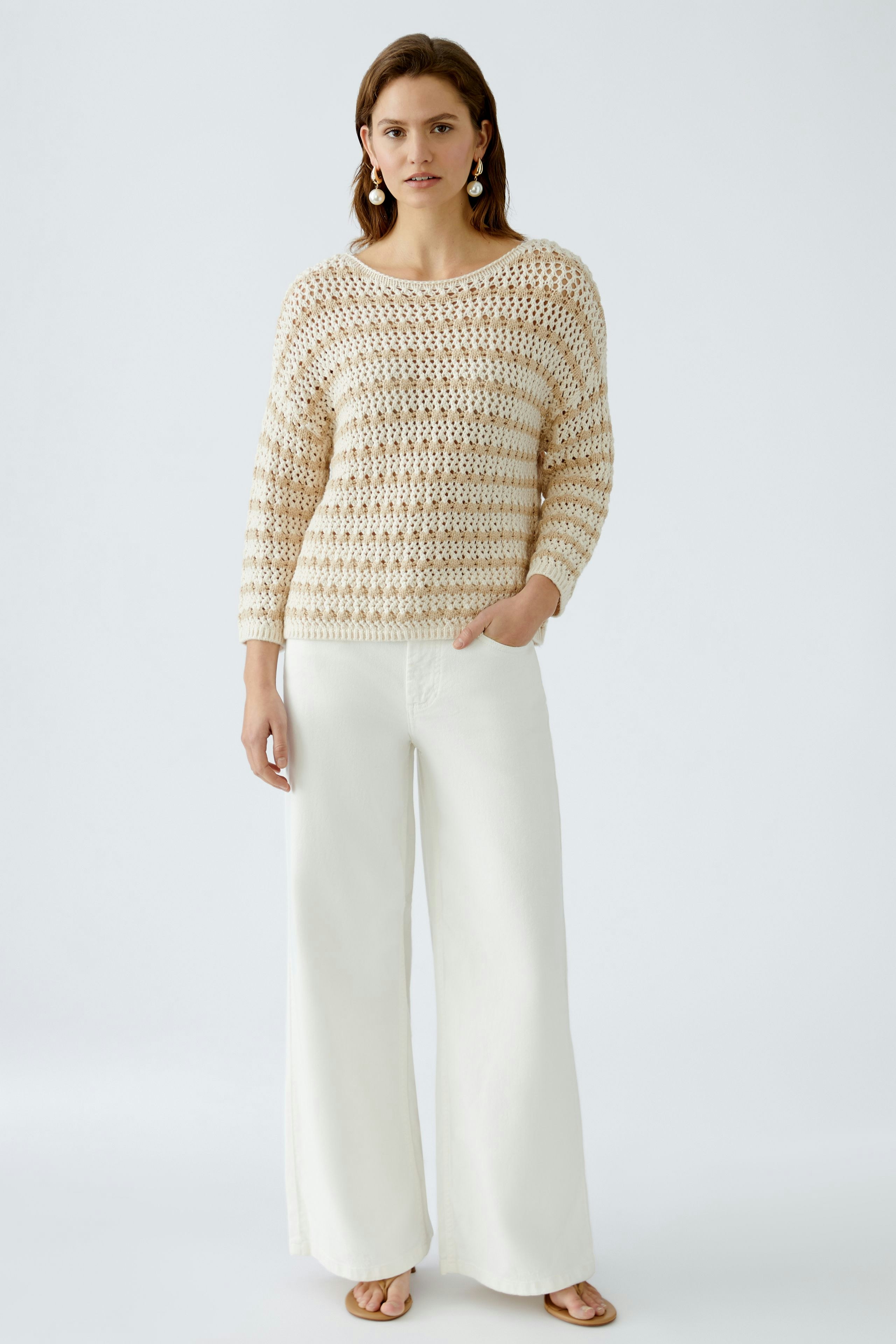 Stylish women's pullover: A woman in a light knitted pullover with a relaxed fit and wide pants.