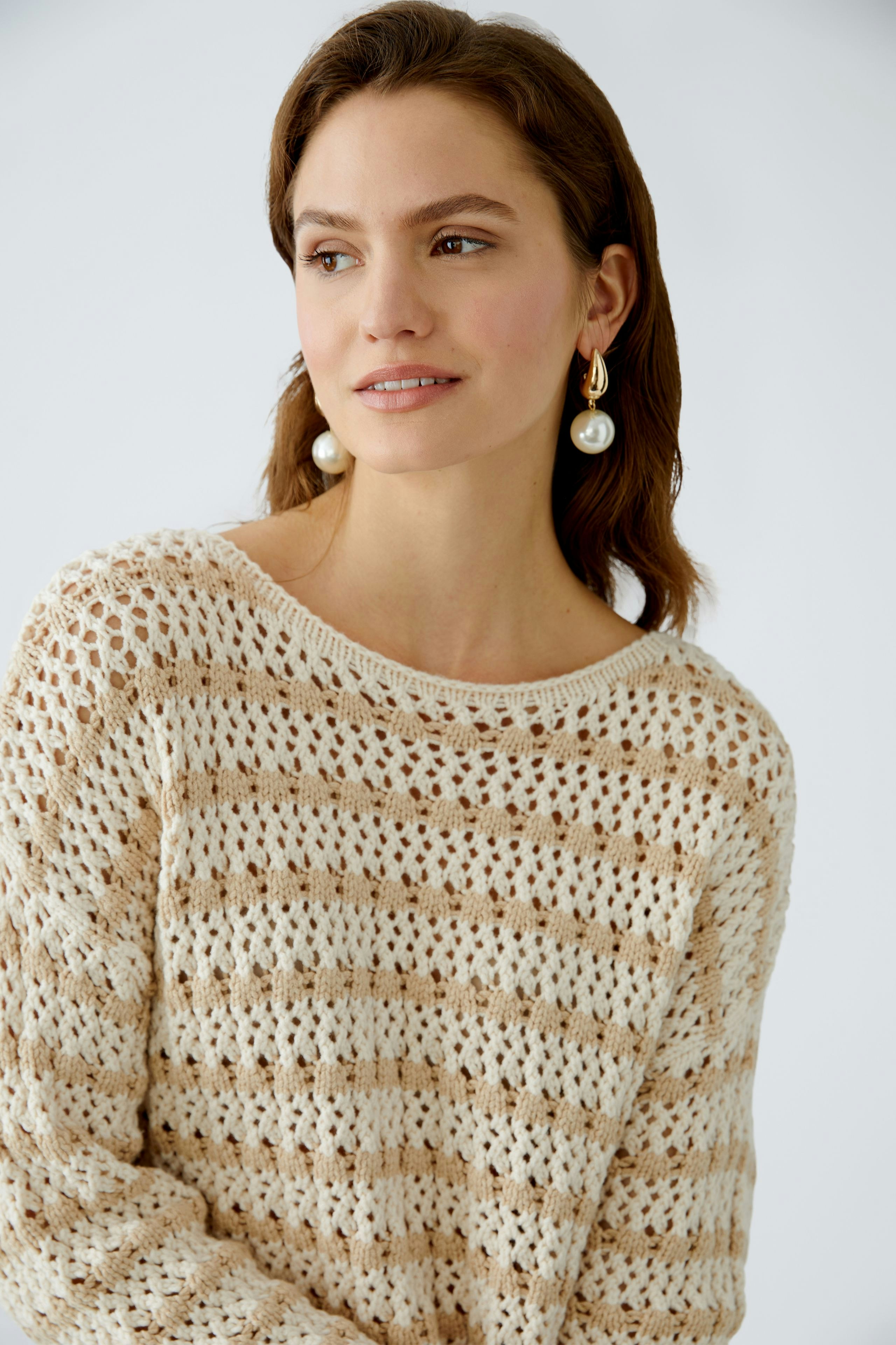 Modern women's pullover: A woman in a light, airy knit pullover with a relaxed fit.