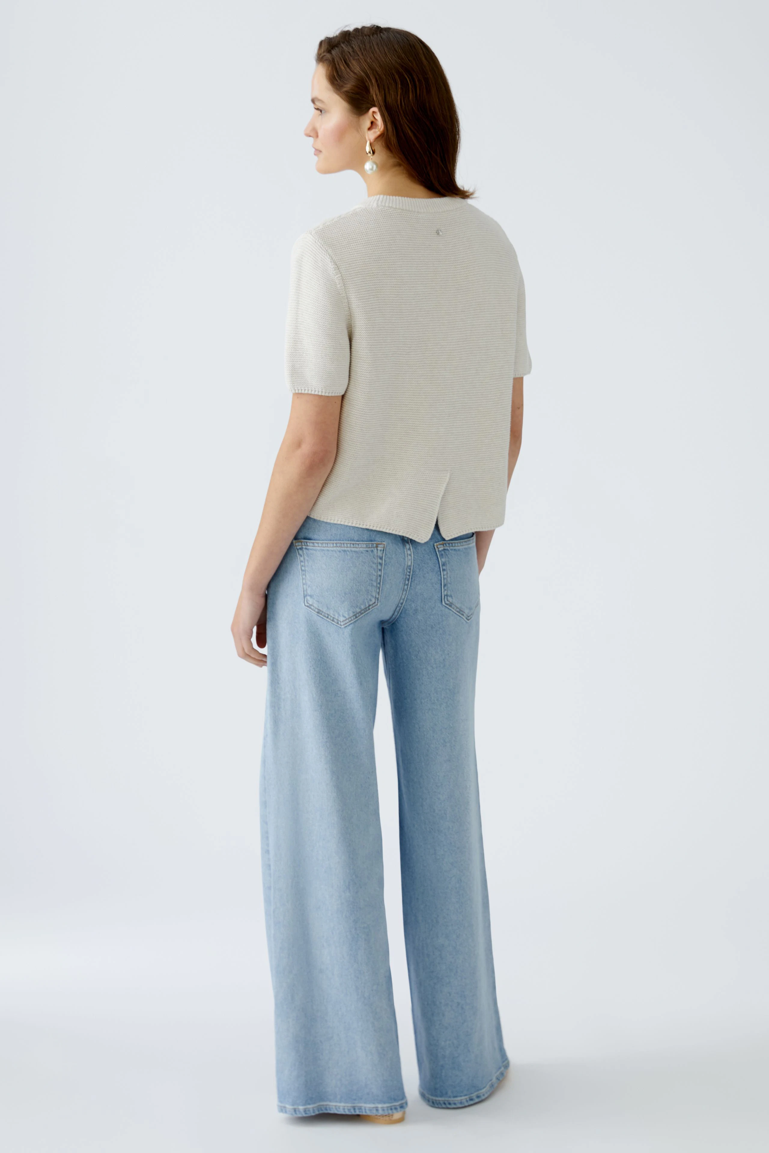 Stylish women's pullover: A woman in a light gray pullover with short sleeves and a relaxed fit.