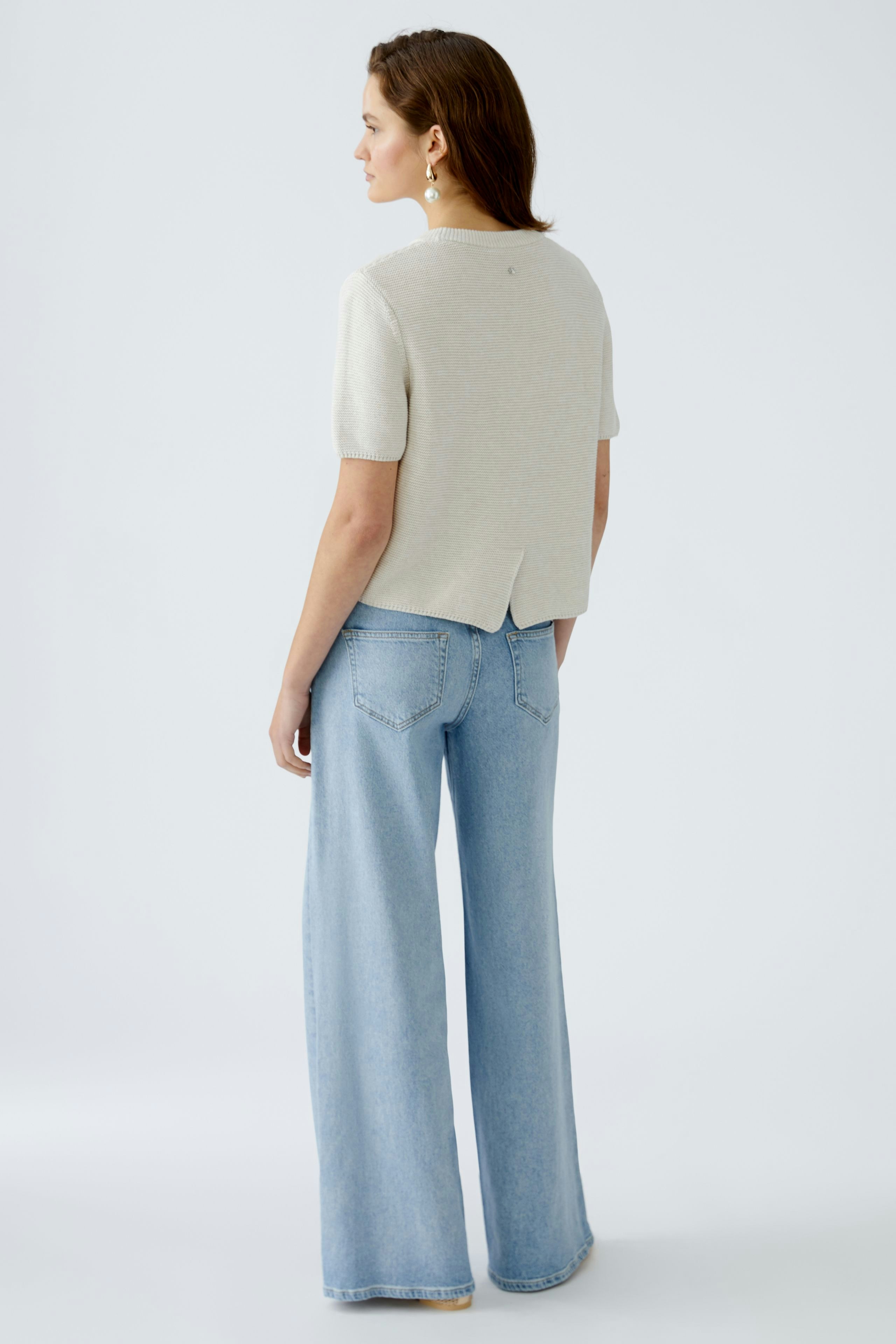 Stylish women's pullover: A woman in a light gray pullover with short sleeves and a relaxed fit.