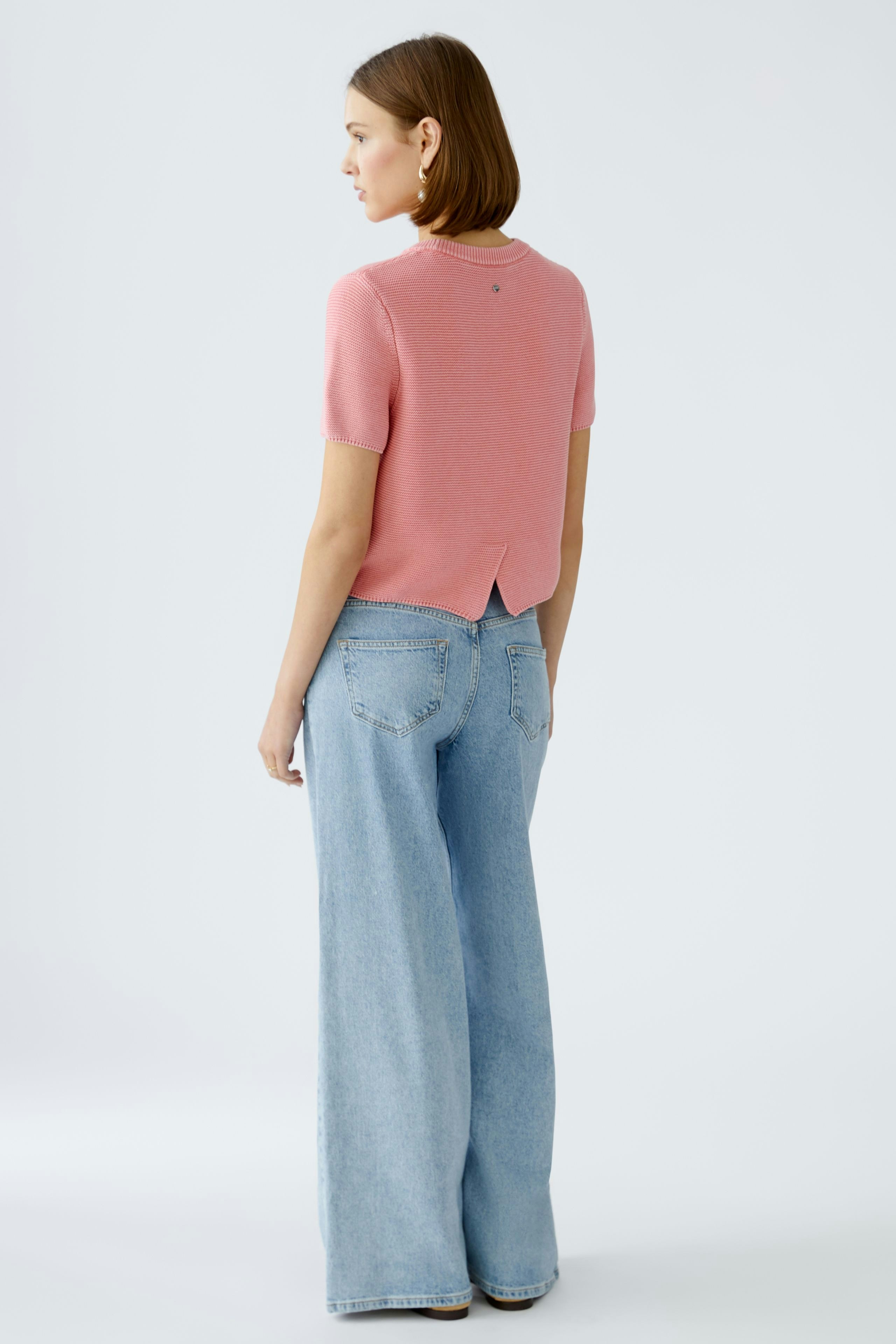 Damen-Pullover: Frau in rosa Strickpullover mit kurzen Ärmeln und lässigen Jeans von hinten.