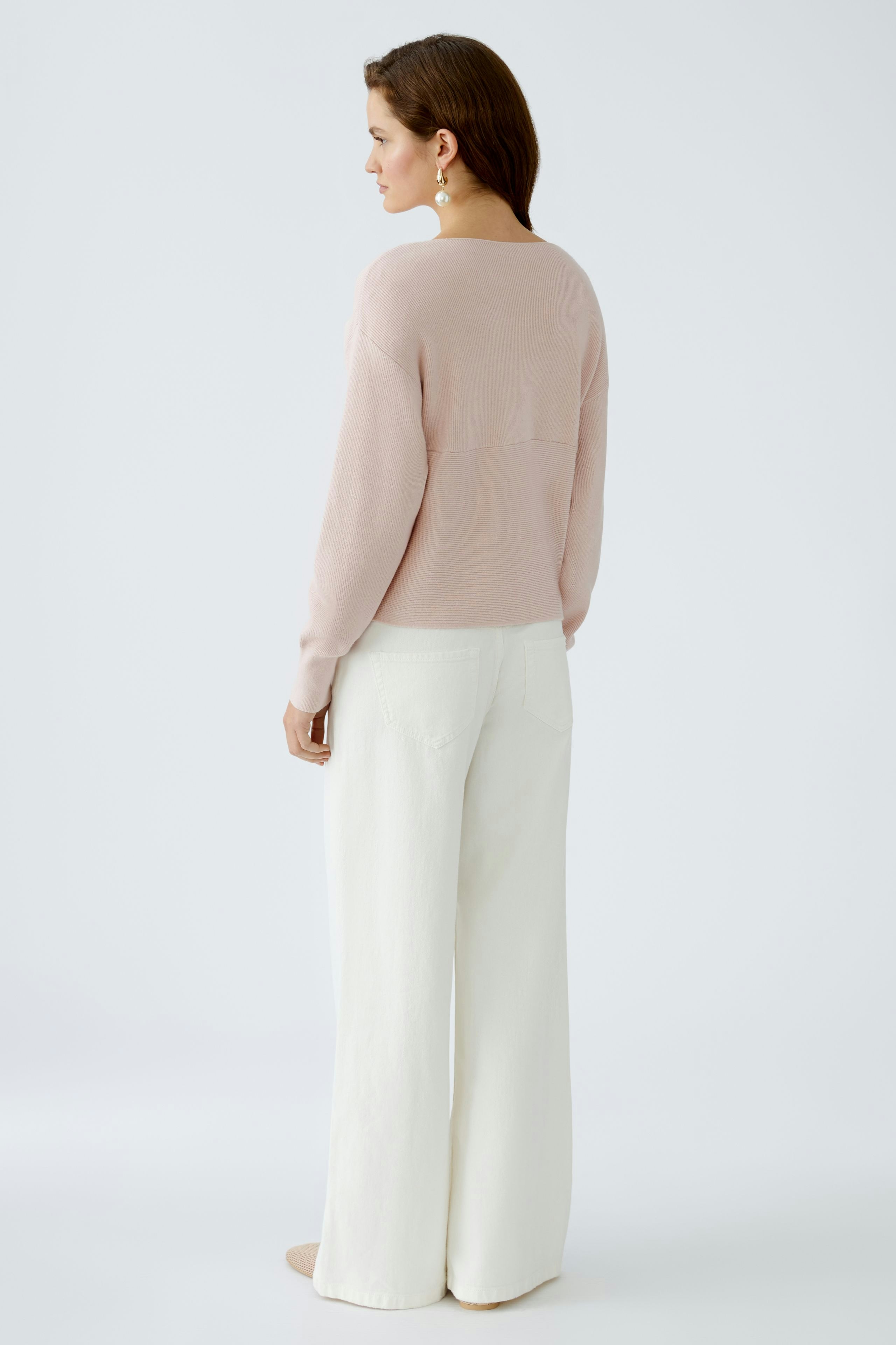 Stylish women's pullover: A woman in a soft pink pullover paired with white wide-leg pants.
