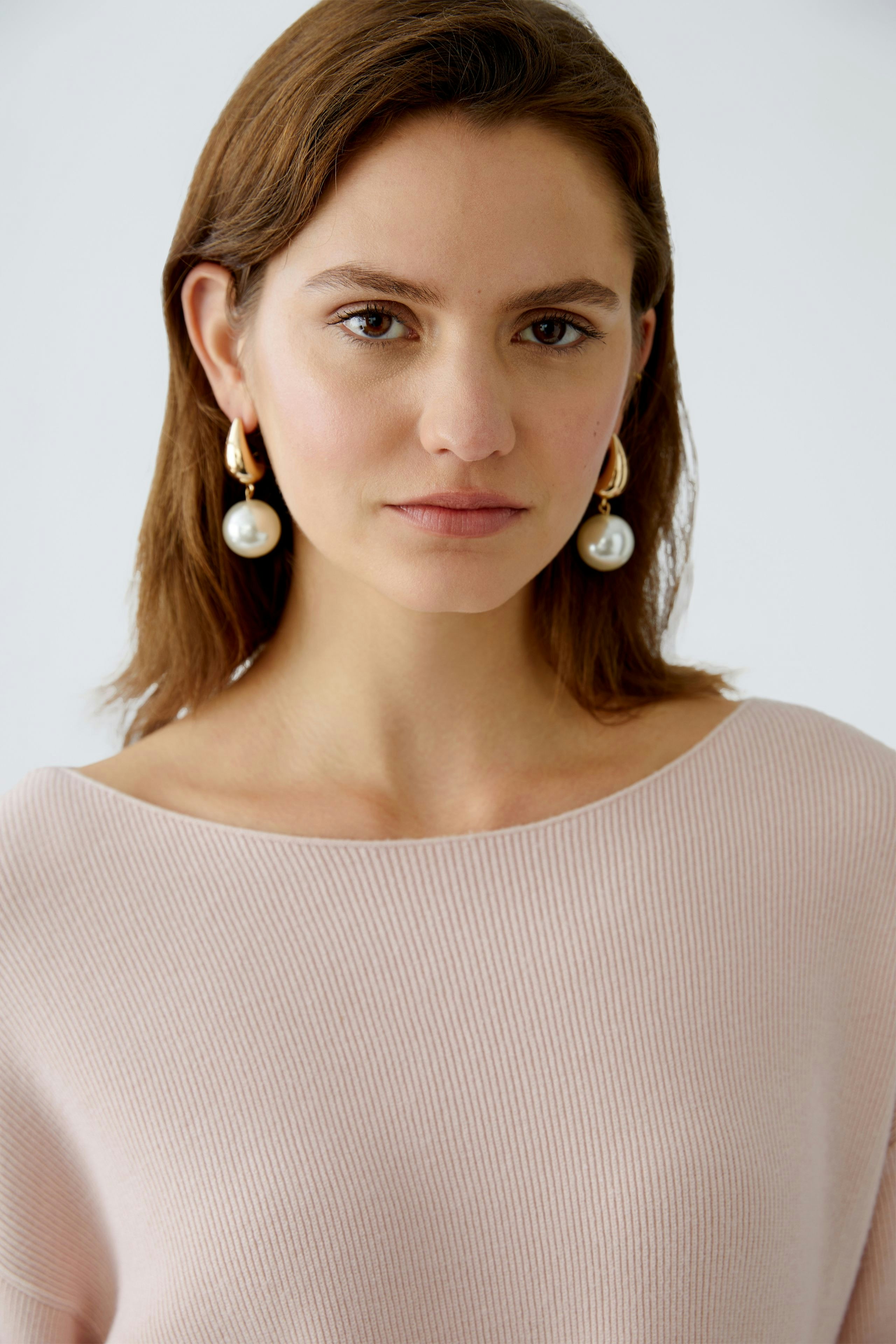 Elegant women's pullover: A woman in a soft pink ribbed pullover, showcasing a relaxed and stylish look.