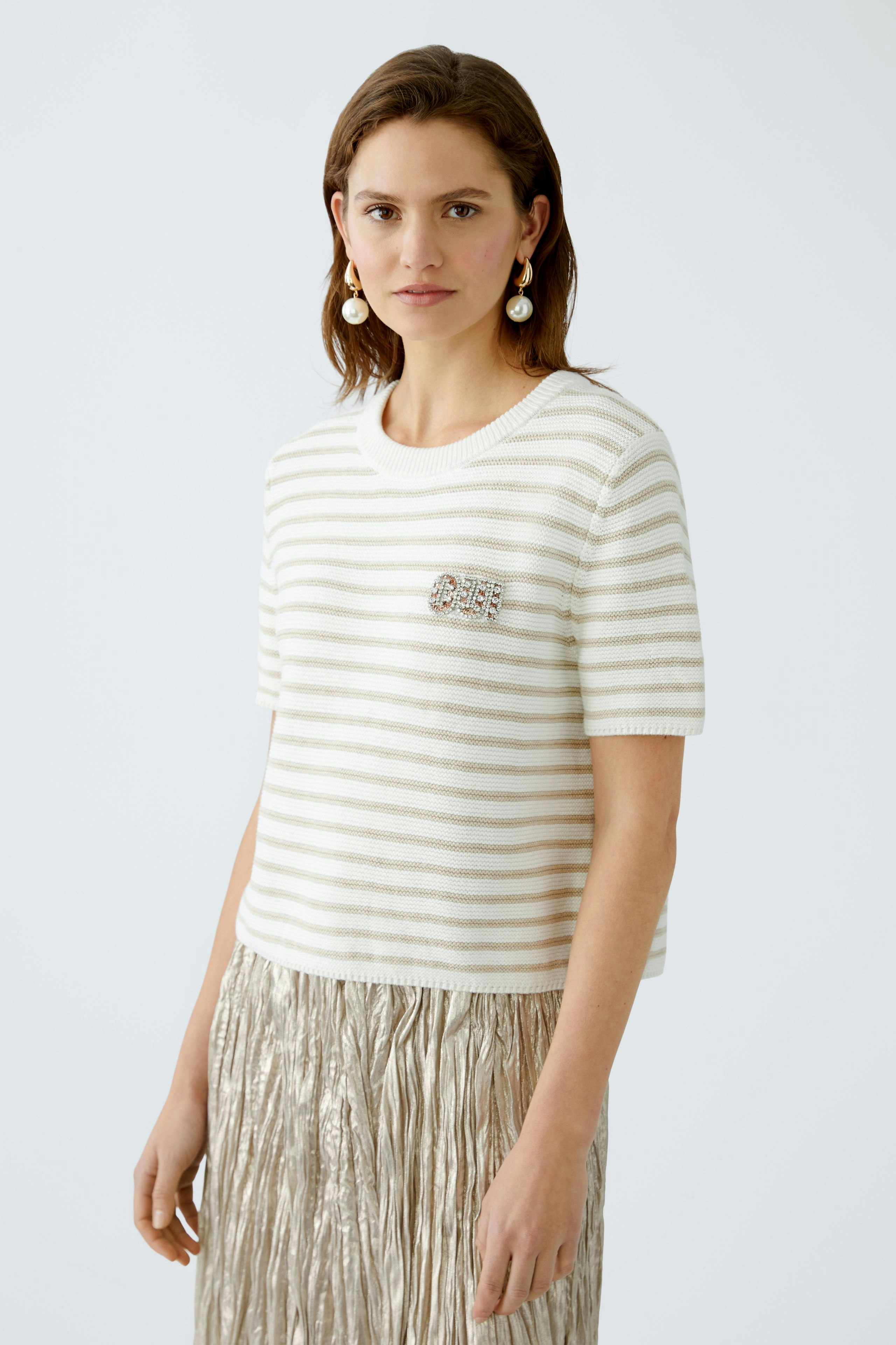 Stylish women's pullover: A woman in a striped pullover with a brooch, paired with a shimmering skirt.