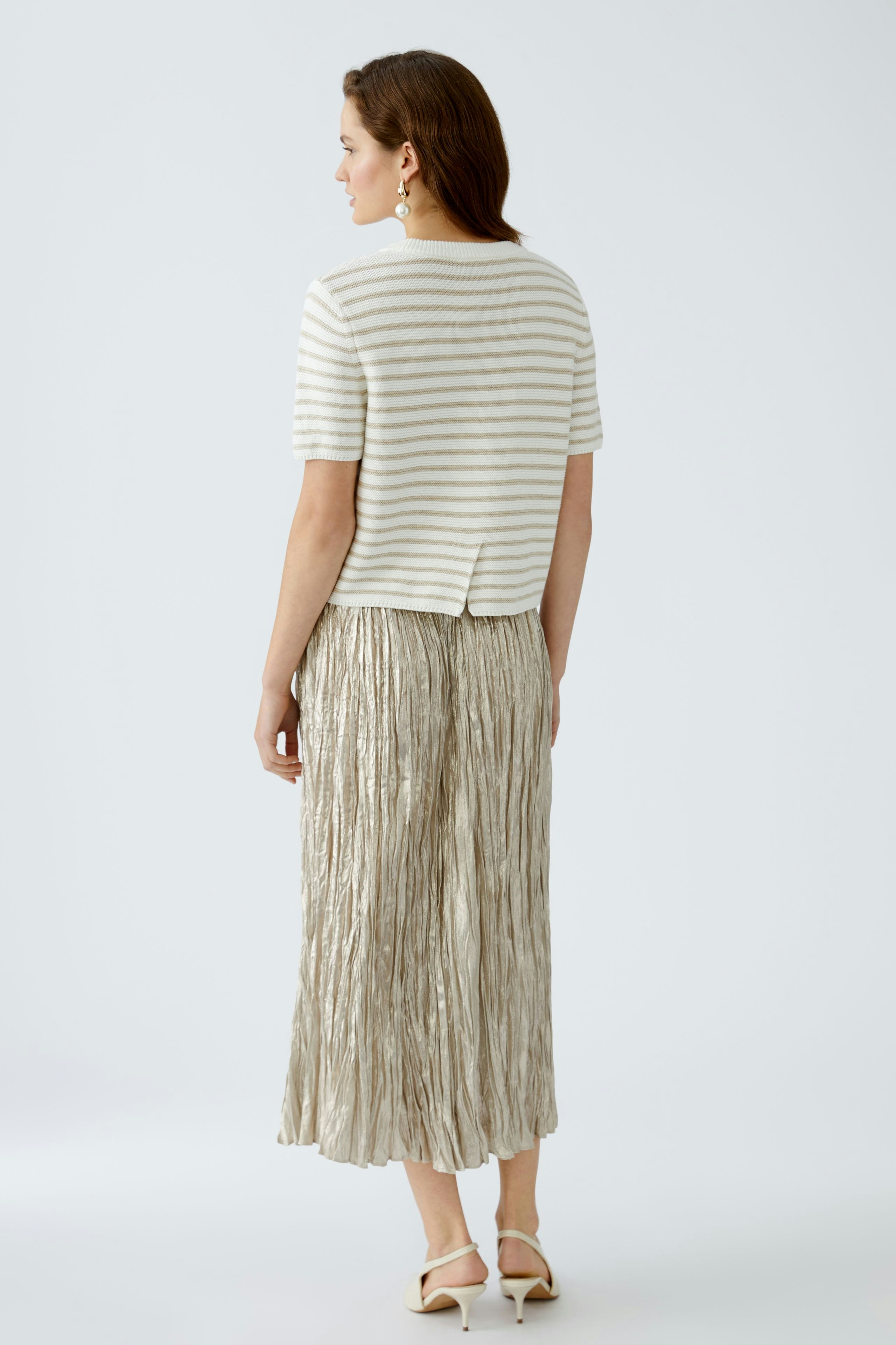 Stylish women's pullover: A woman in a striped pullover paired with a pleated skirt, exuding elegance.