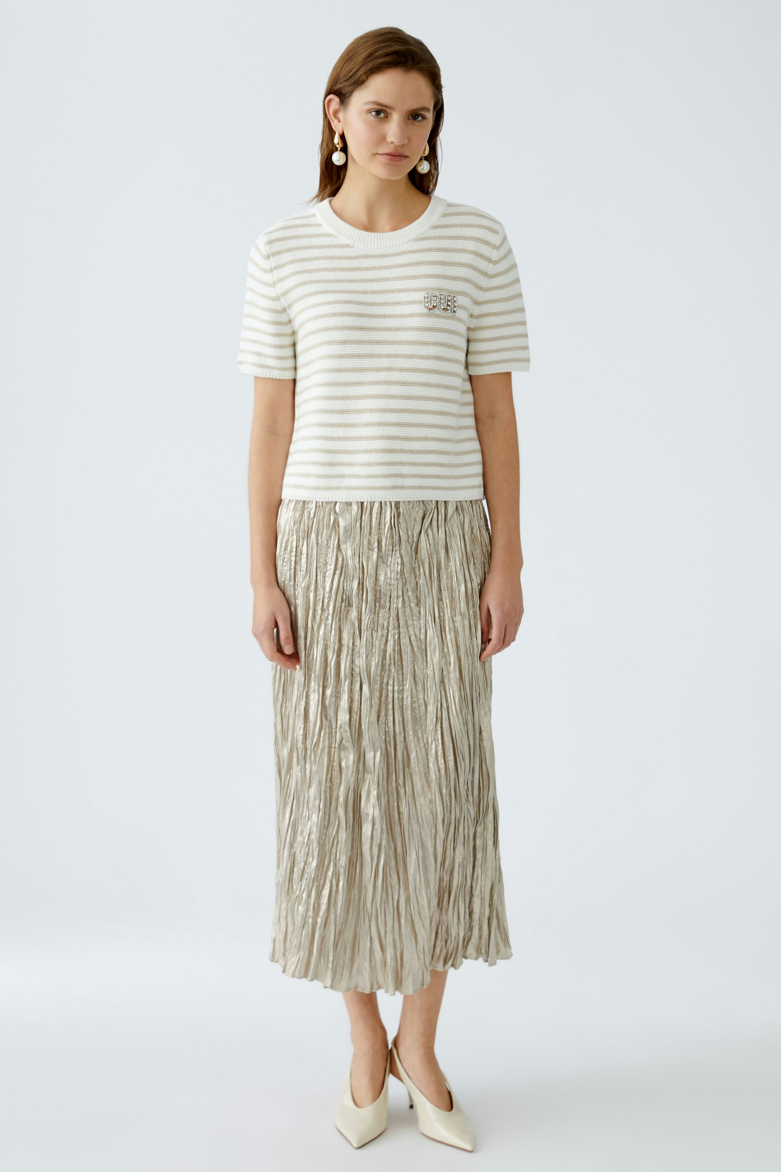 Stylish women's pullover: A woman in a striped pullover paired with a pleated skirt, exuding elegance.