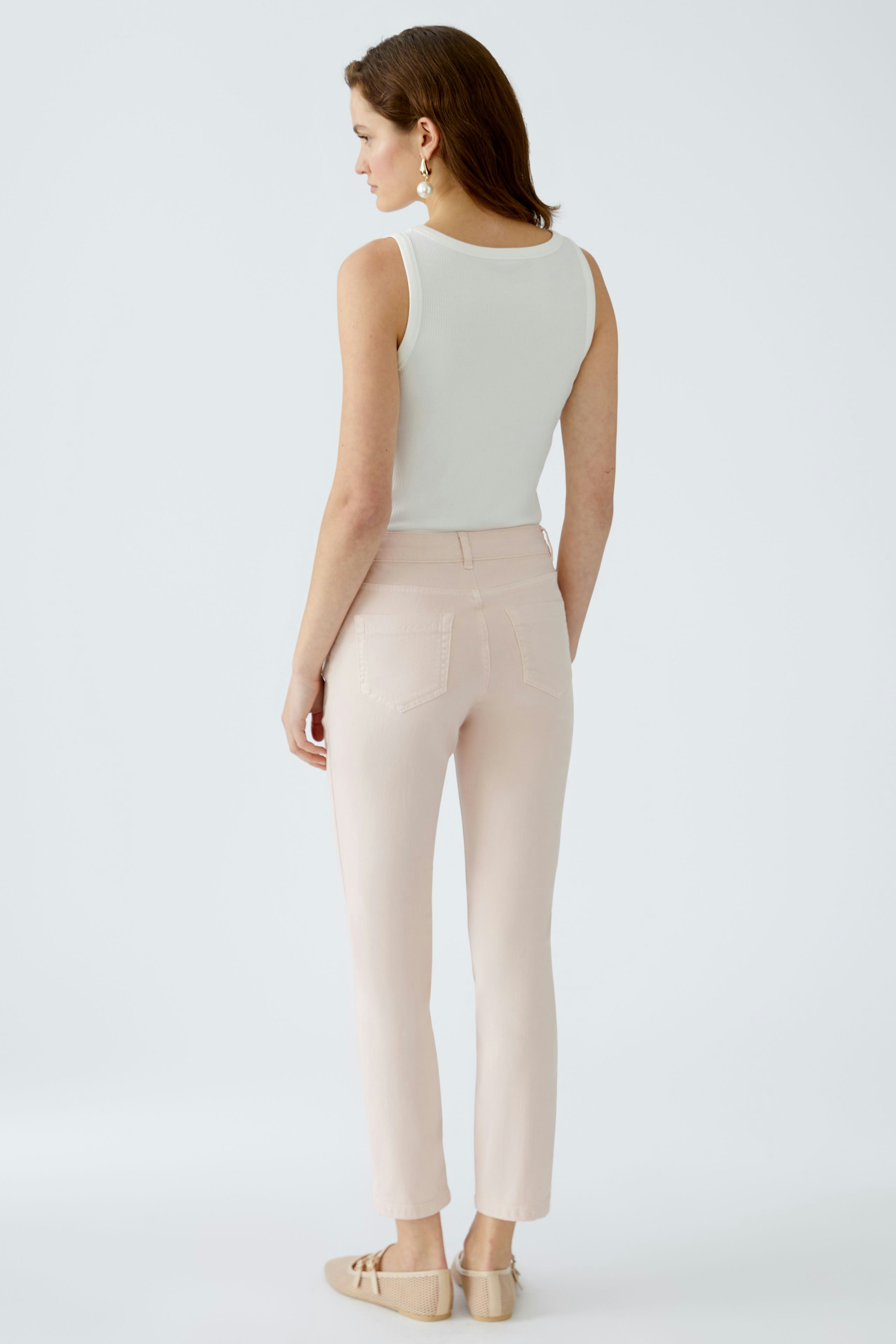 Elegante Jeggings: Frau in hellen Jeggings mit schmalem Schnitt und lässigem Oberteil von hinten.