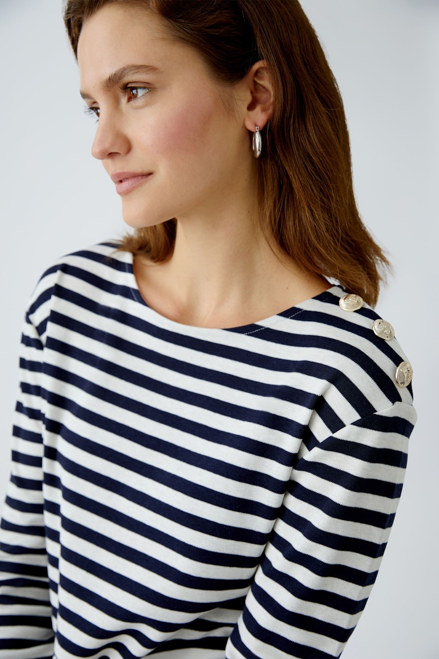 Stylish long-sleeve shirt: Woman in a navy and white striped pullover with button details.