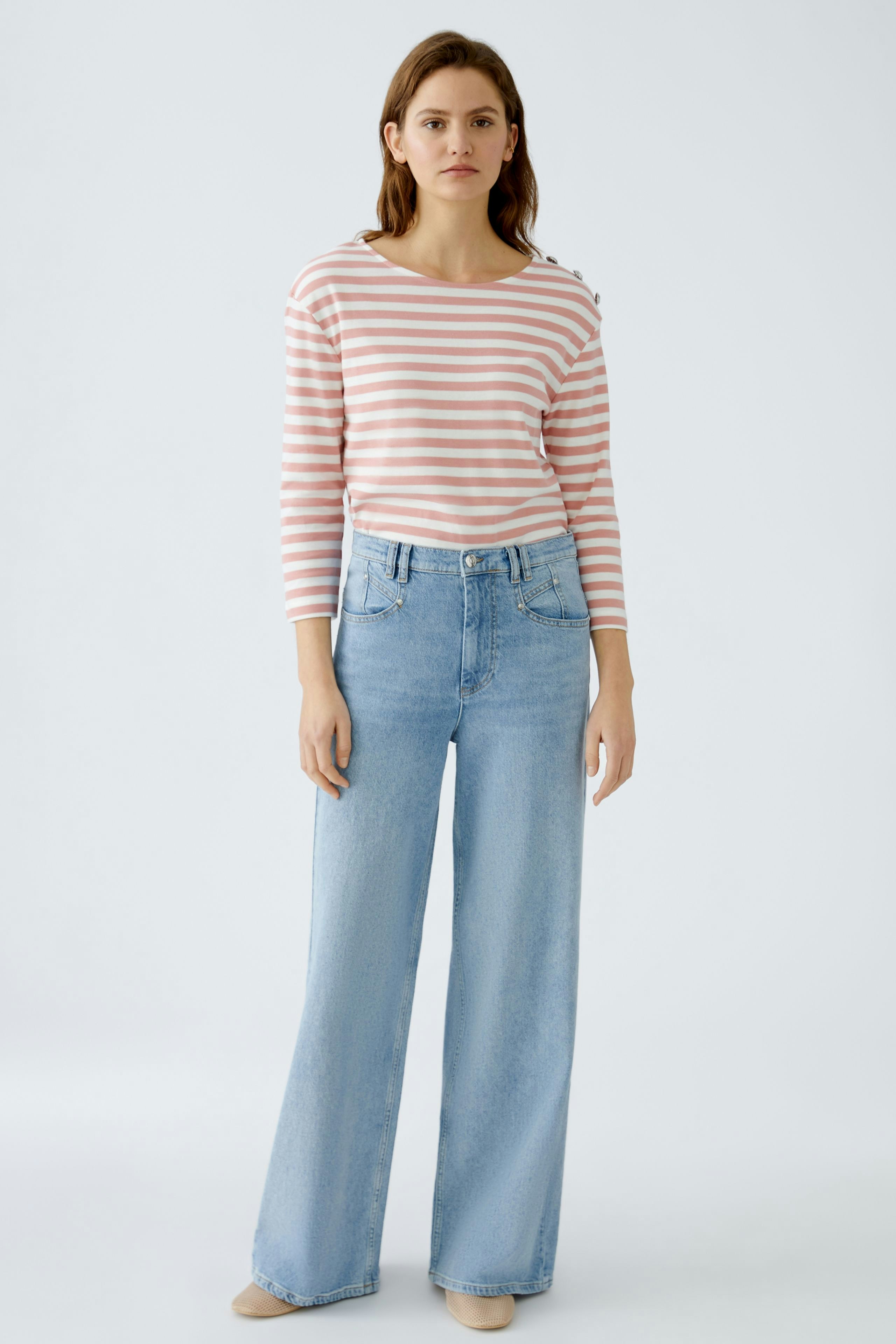 Damen Langarmshirt: Frau in gestreiftem Shirt mit langen Ärmeln und lässigen Jeans.