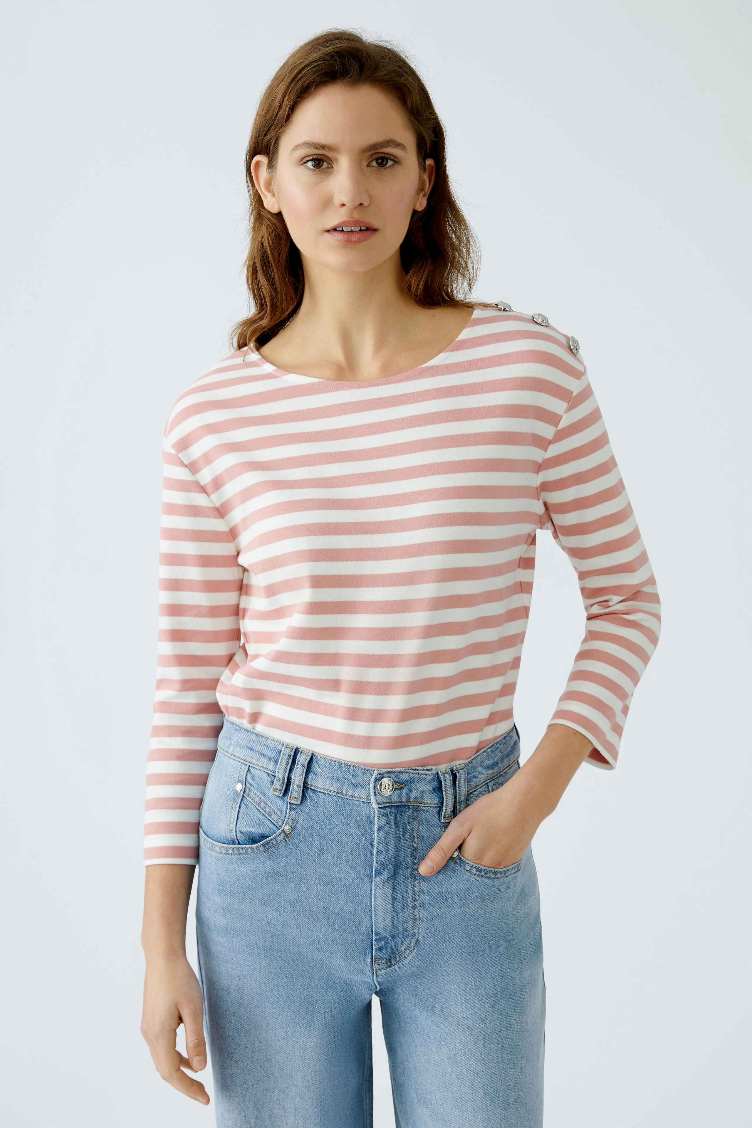 Langarmshirt: Junge Frau in gestreiftem Langarmshirt mit Knöpfen an der Schulter und lässiger Jeans.