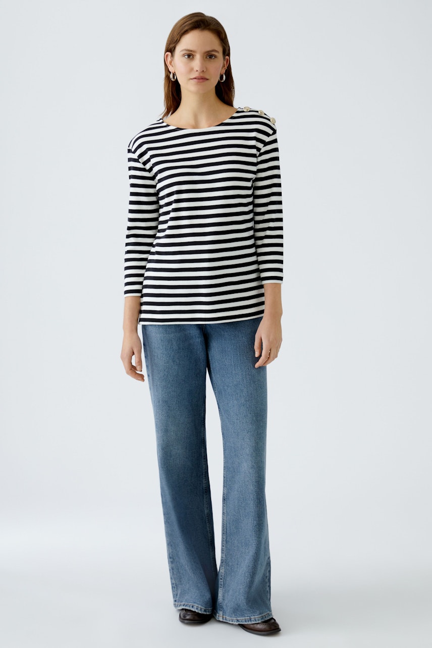 Stylish women's long-sleeve shirt: A woman in a striped top paired with flared jeans.