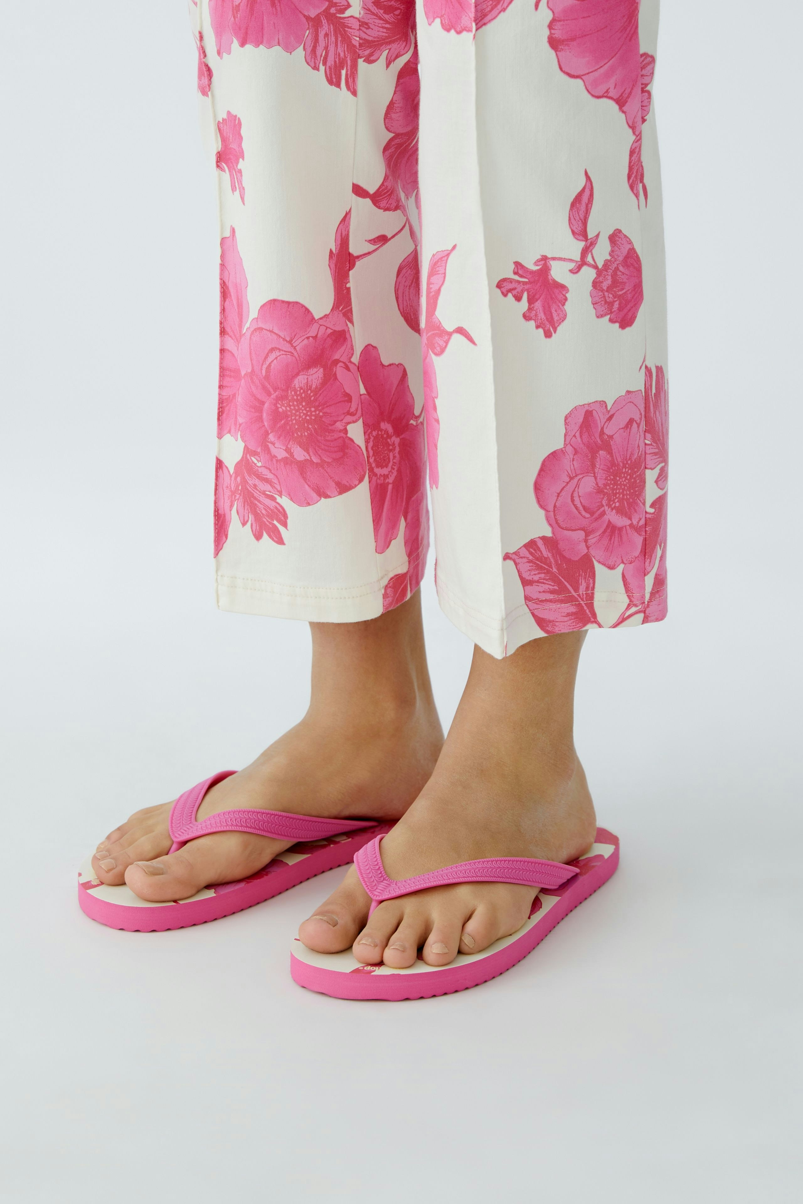 Bequeme Damen-Sandalen: Frau trägt pinke Flip-Flops zu floralem Outfit.