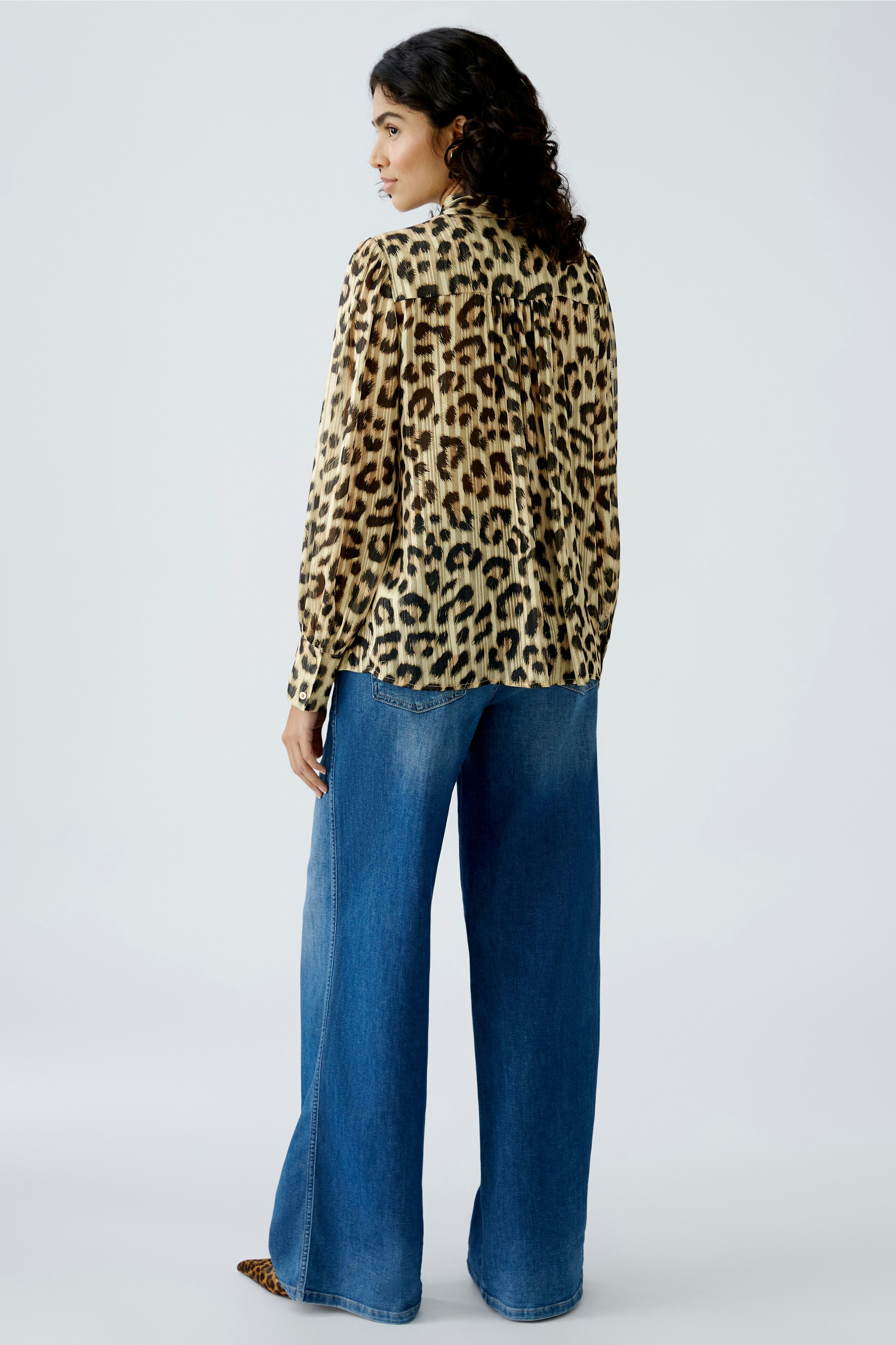 Stylish women's blouse: A woman in a leopard print blouse paired with wide-leg jeans.