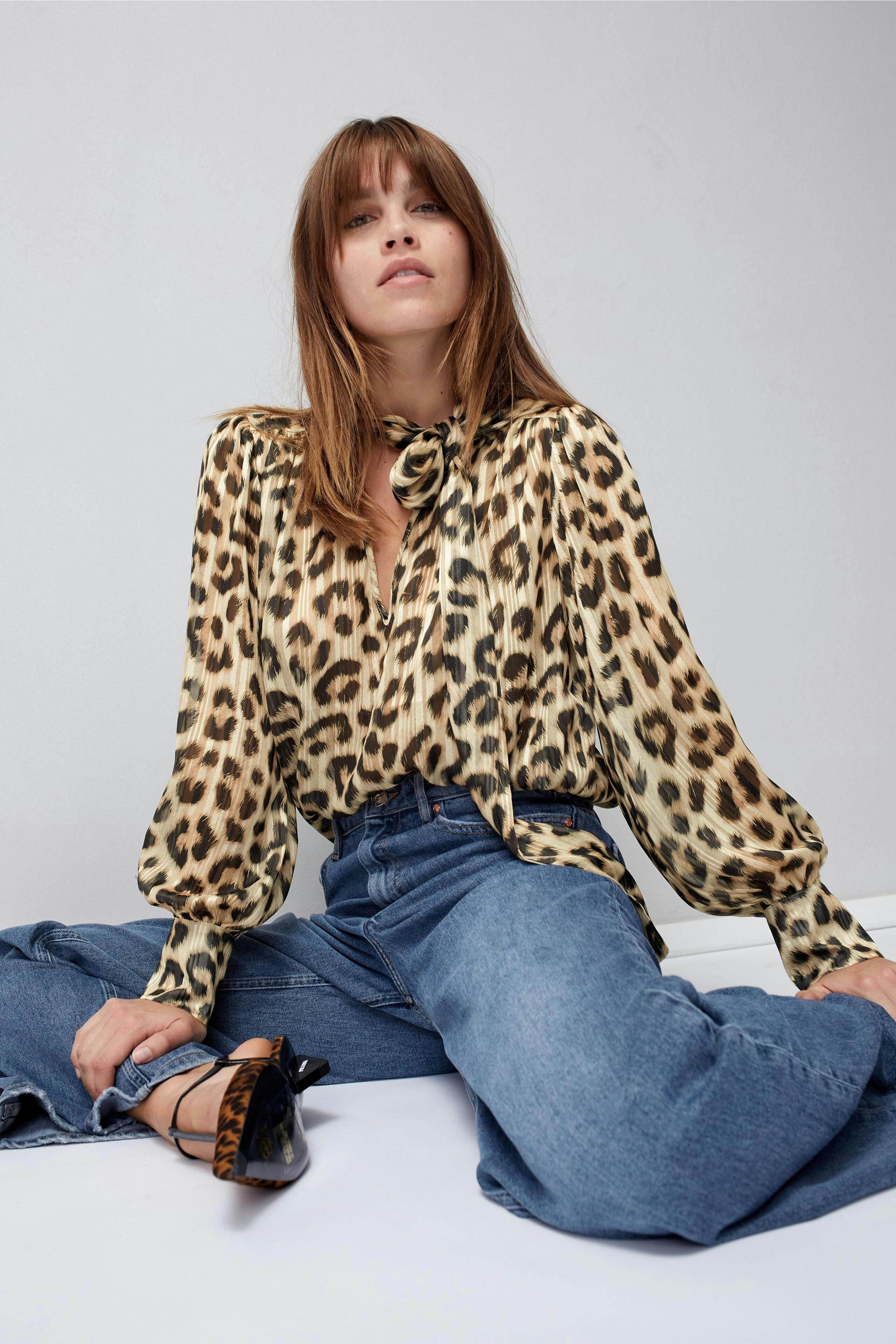 Stylish women's blouse: A woman in a leopard print blouse paired with denim, exuding confidence.