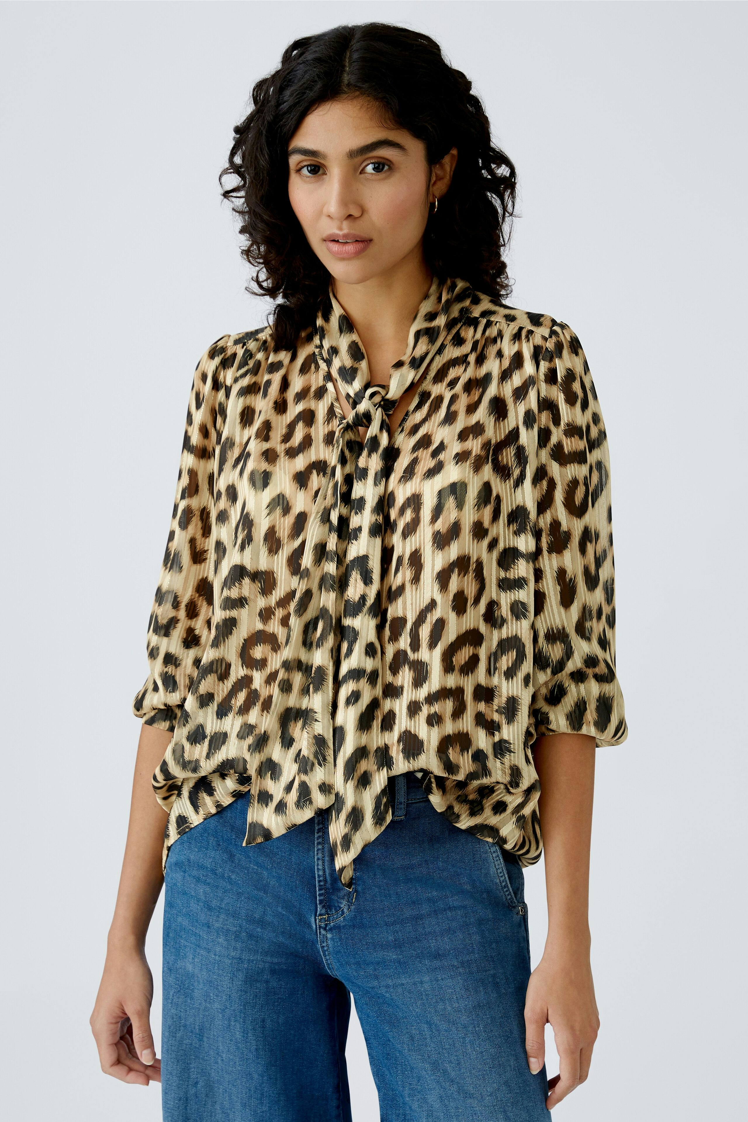 Stylish women's blouse: A woman in a leopard print blouse with a tie detail, paired with casual jeans.