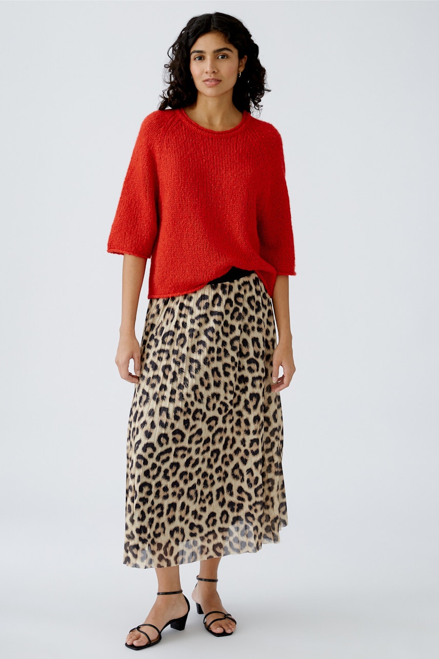 Stylish women's pullover: A woman in a red textured pullover paired with a leopard print skirt.