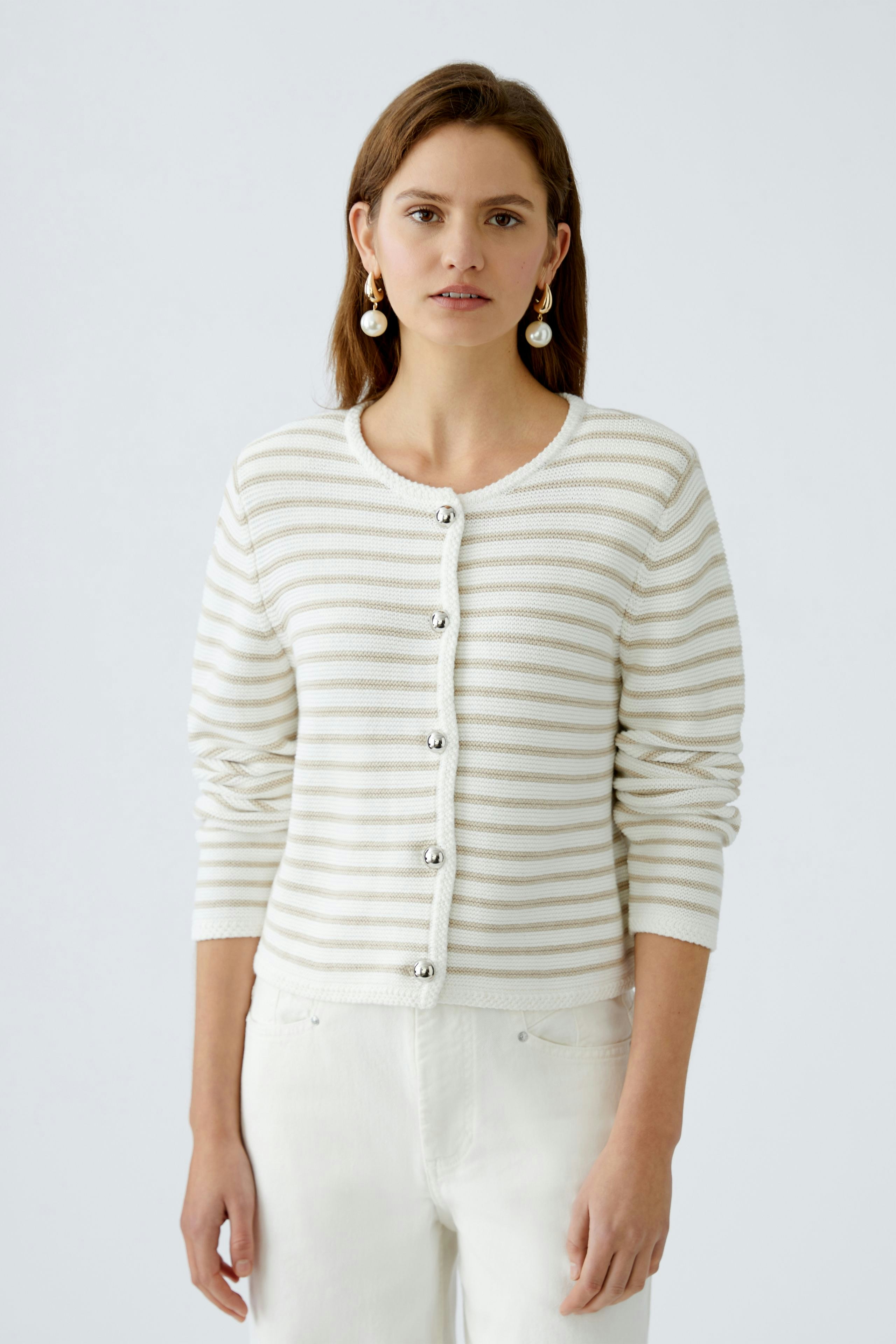 Stylish women's cardigan: A woman in a striped cardigan with buttons, paired with light trousers.