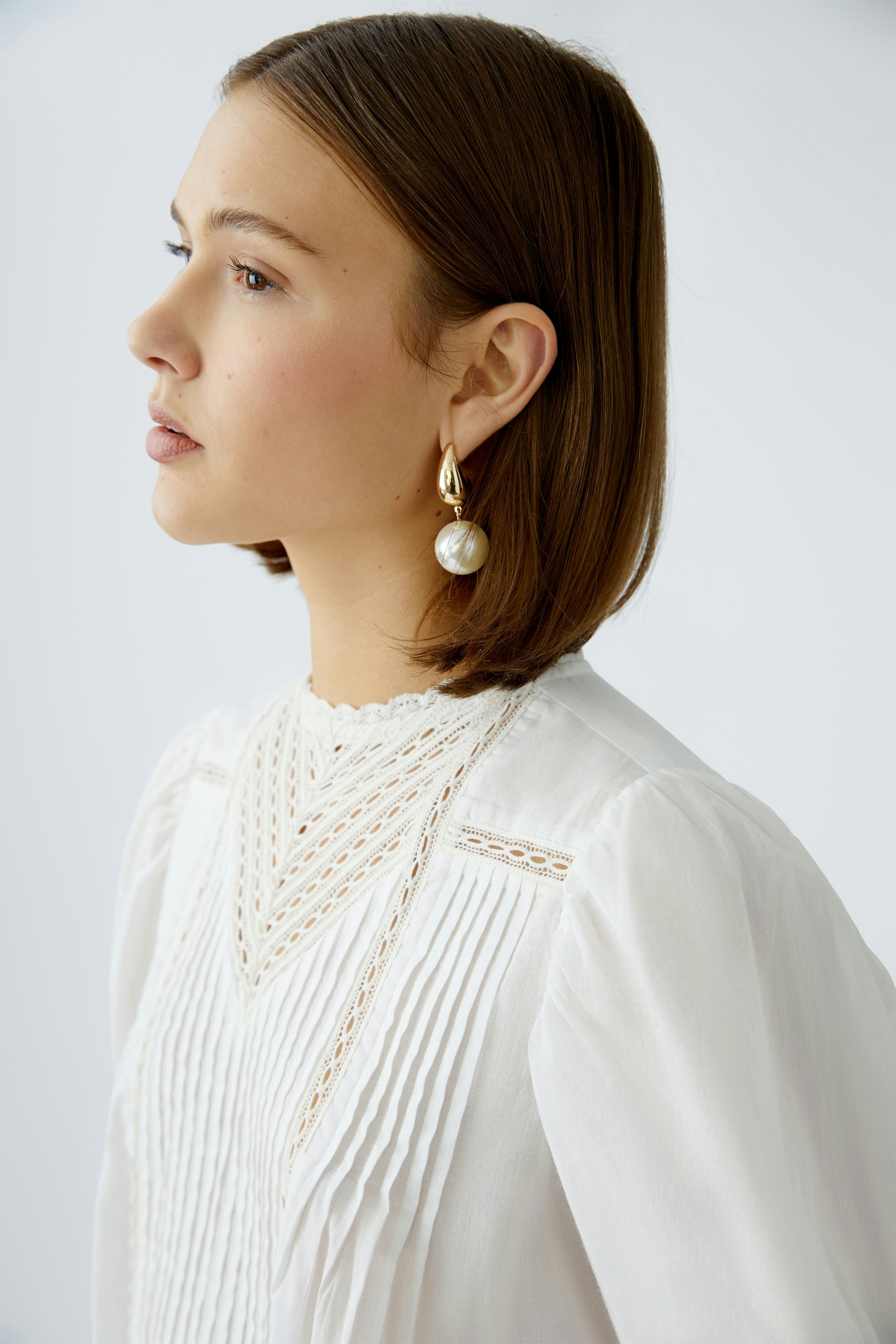 Elegante Damen-Bluse: Frau mit feiner, weißer Bluse und dekorativen Details im Profil.
