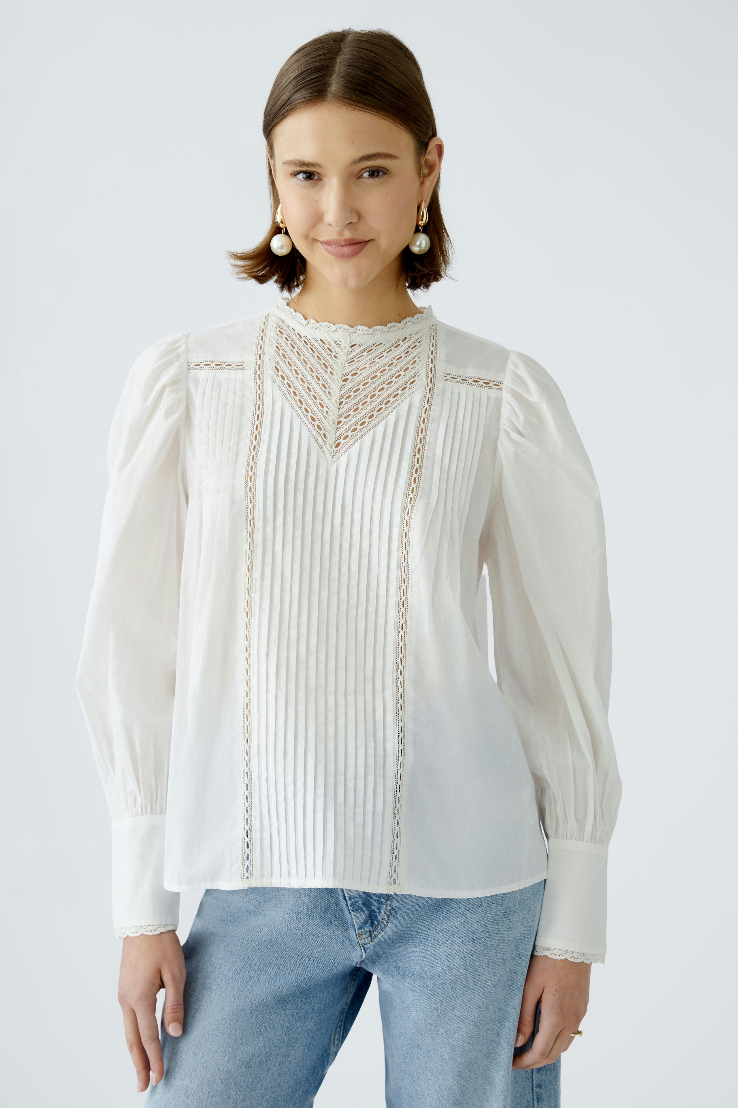 Elegante Damen-Bluse: Frau trägt eine weiße Bluse mit feinen Falten und Spitzenakzenten.