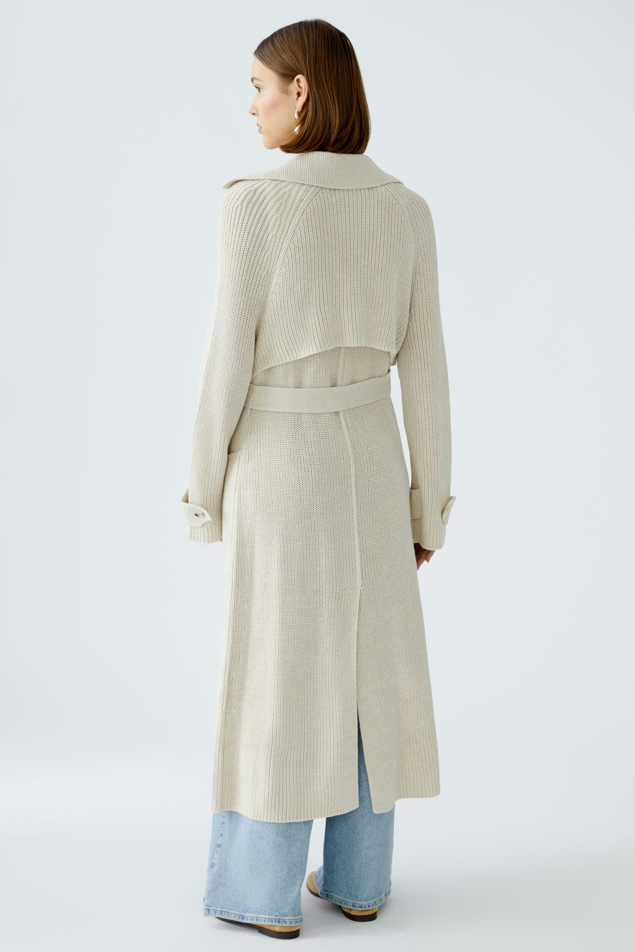 Stylish women's cardigan: A woman in a light beige knitted cardigan with a belted waist and open back.