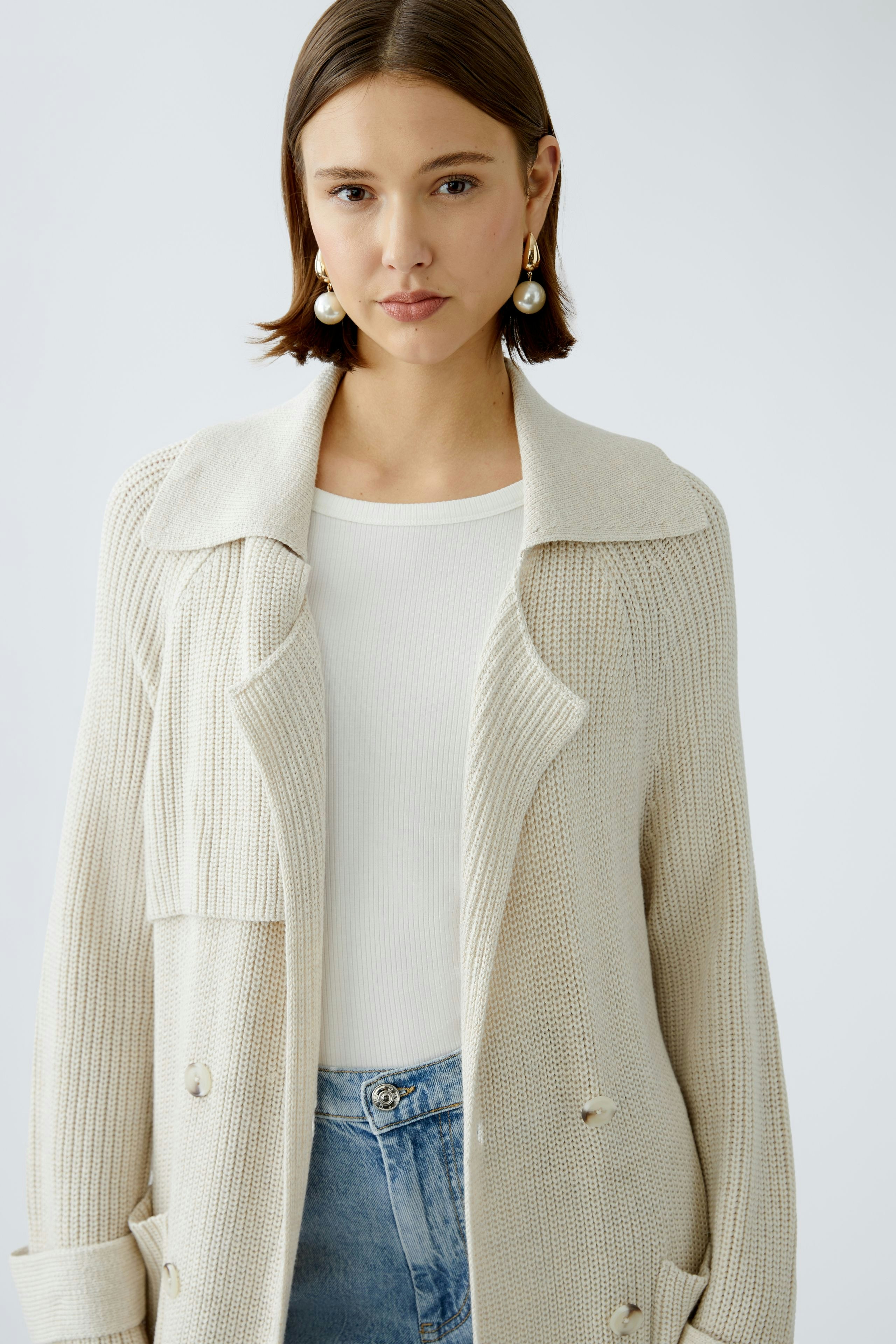 Stylish women's cardigan: A woman in a cream knitted cardigan over a white top and jeans.