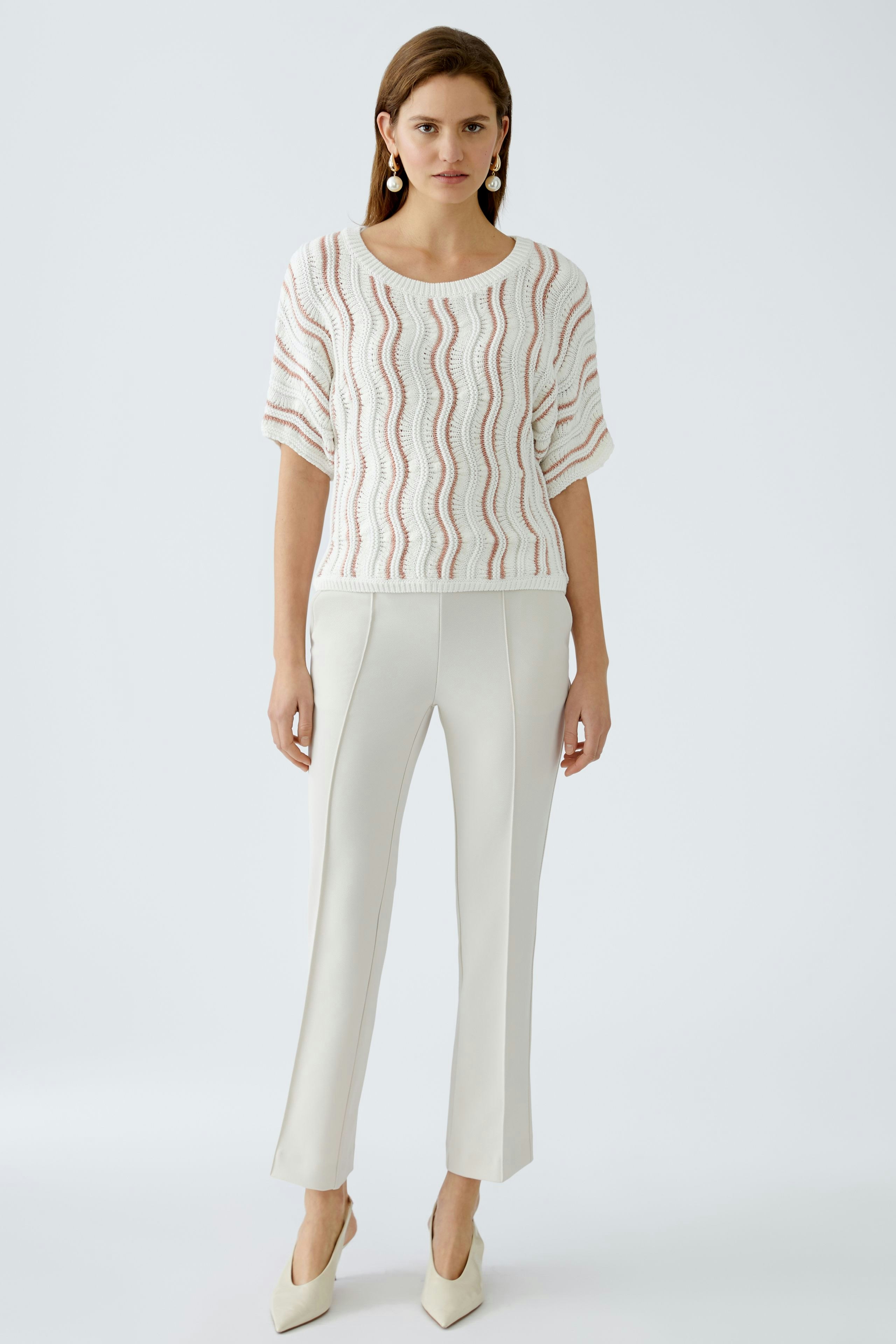 Elegant women's trousers: A woman in cream-colored fitted trousers stands confidently.