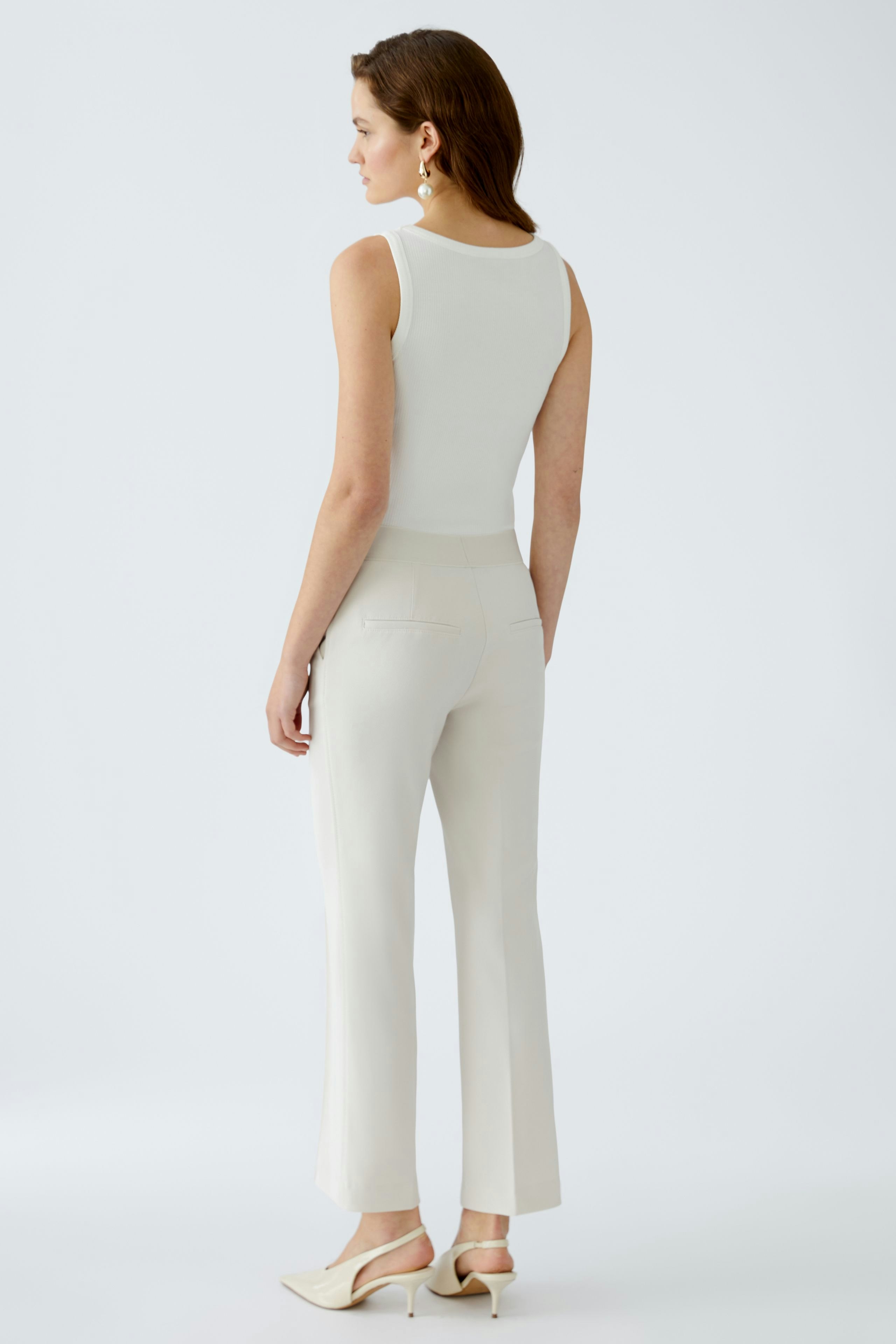 Elegant women's trousers: A woman in fitted cream trousers, showcasing a sleek and modern silhouette.