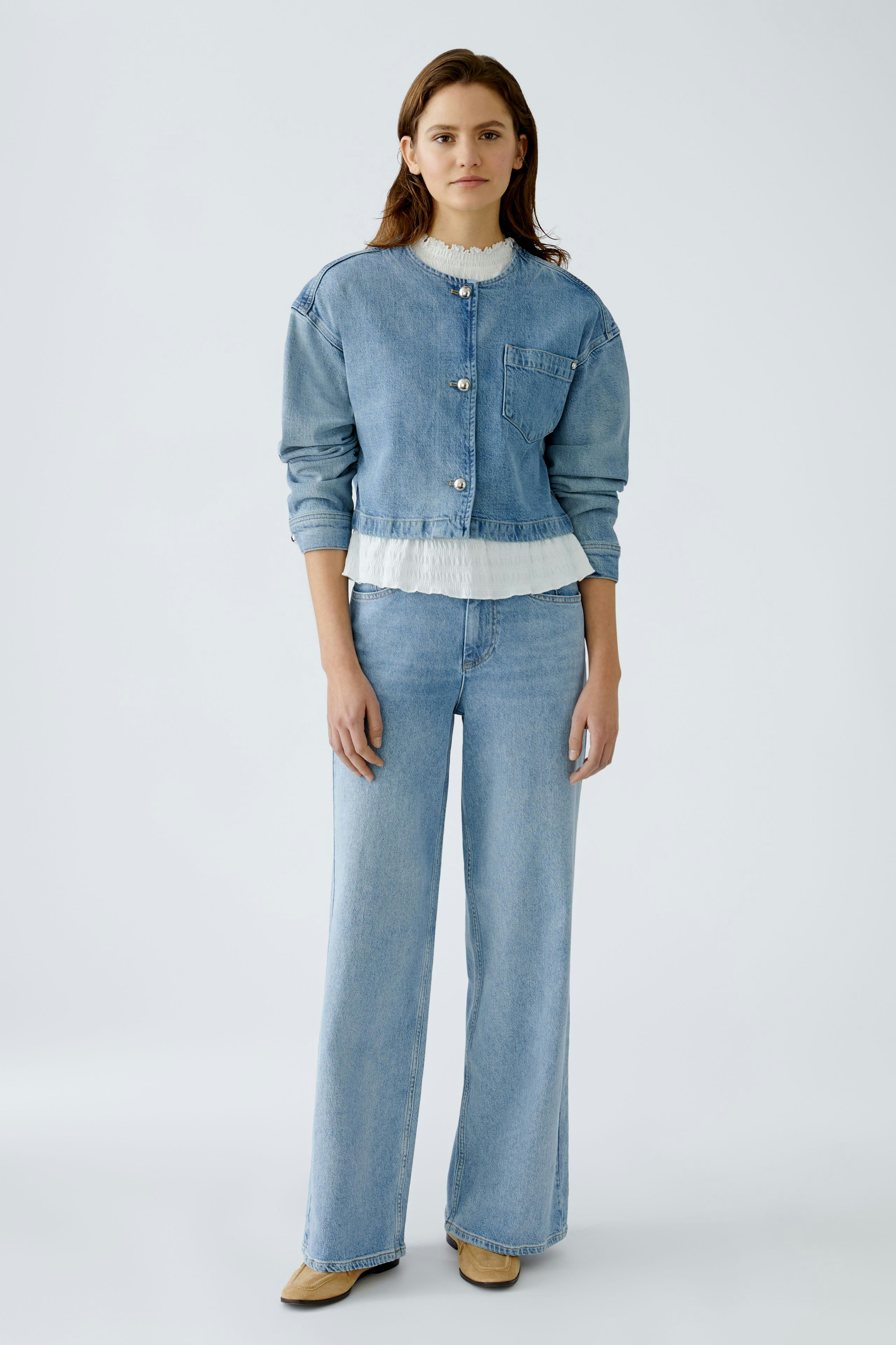 Moderne Jeansjacke: Junge Frau in lässiger Jeansjacke mit Knöpfen und frischem Look steht selbstbewusst.